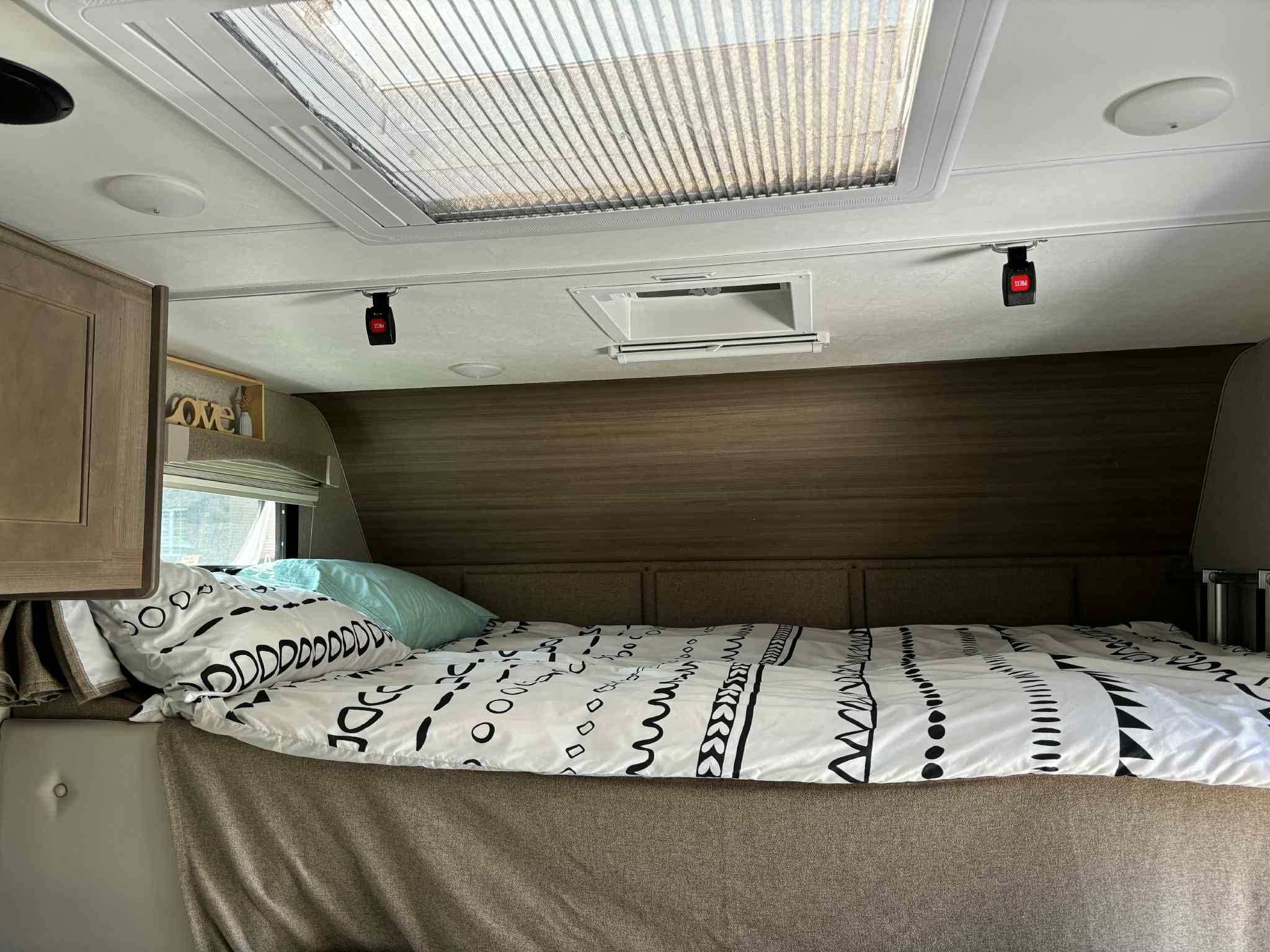 RV rental interior: Comfortable bed with patterned duvet, bright skylight, and overhead safety buckles.. Adventurer 23RD 2022