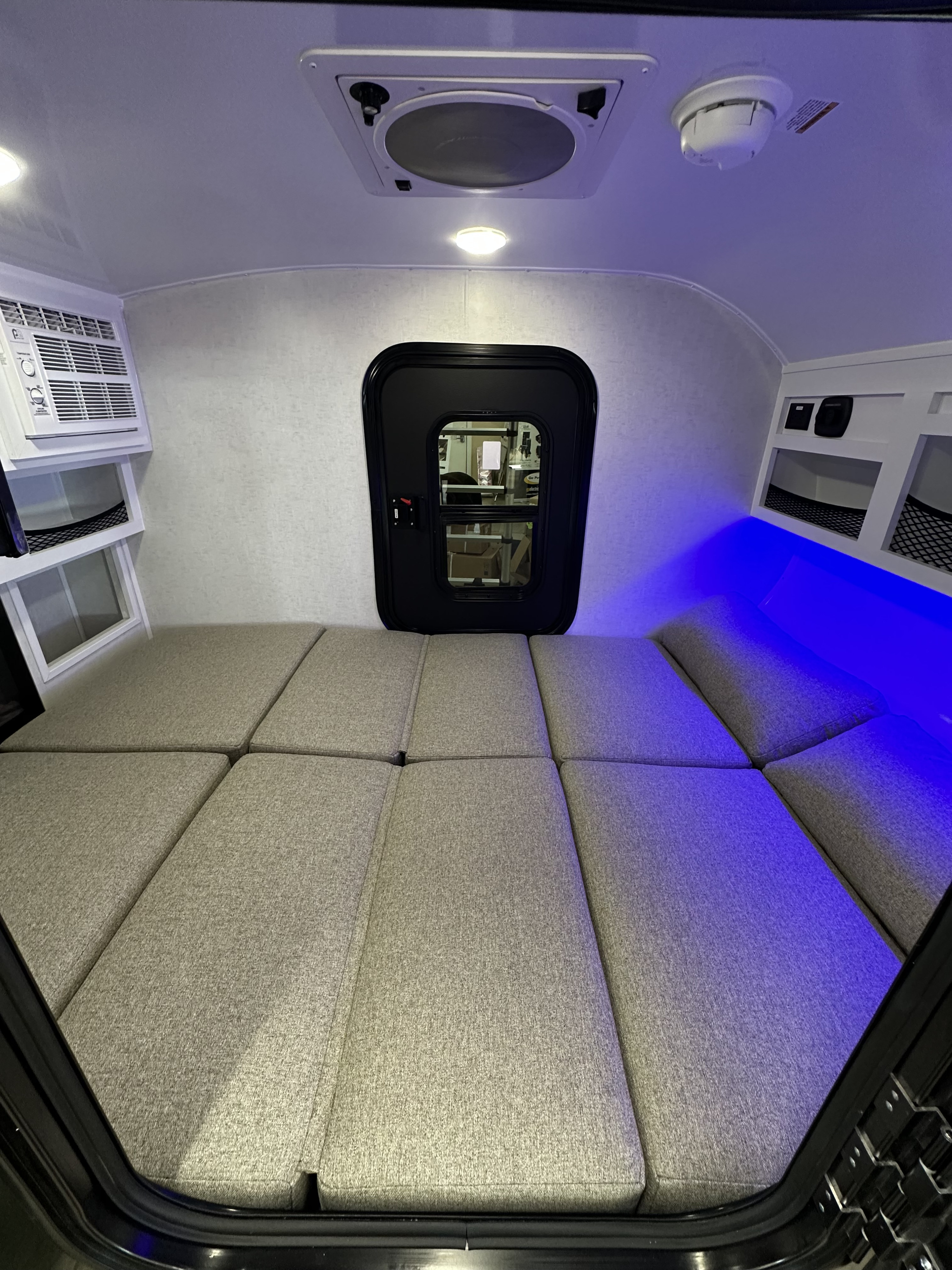 RV rental interior featuring a versatile bed/seating area, AC, and ambient blue lighting, ready for comfort on the road.. ModernBuggyRV 12LKR 2026