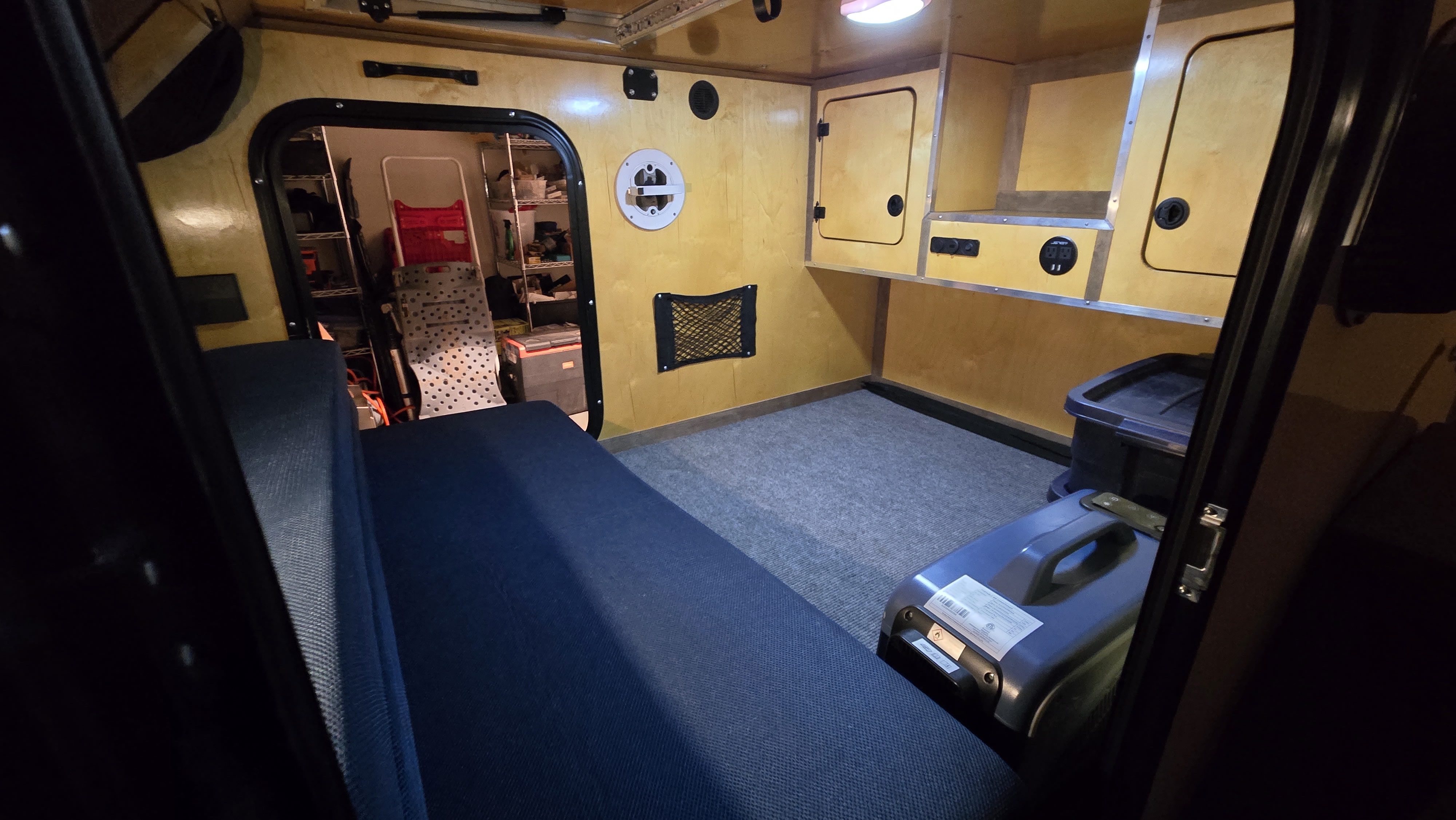 Cozy RV rental interior featuring a bed, wood-paneled walls, storage, and a portable power station for comfortable travels.. Venture Overland Campers XTR OFFROAD 2024