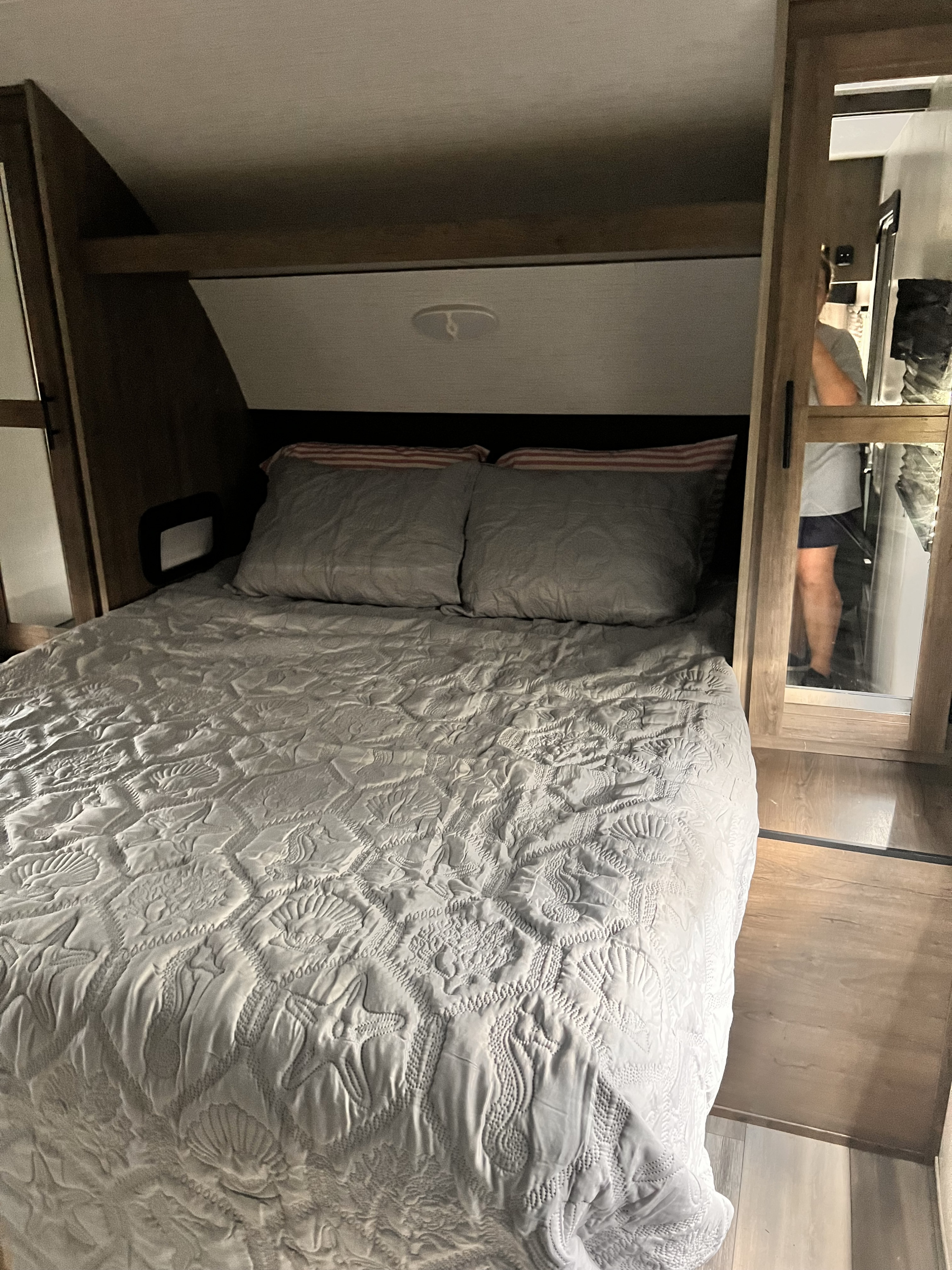RV rental bedroom with a cozy bed featuring a quilted sea-themed comforter and mirrored closet visible.. Heartland RVs Pioneer 2023