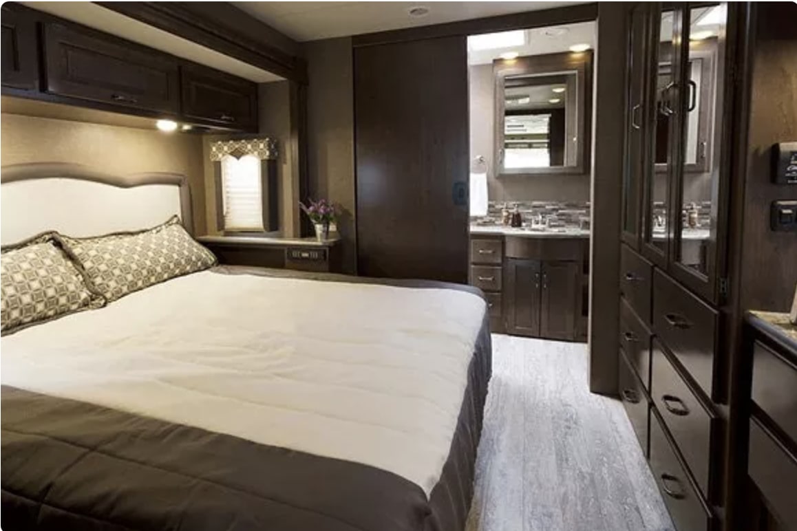 Comfortable RV rental bedroom featuring a large bed, vanity, and ample storage.. Thor Hurricane 2018