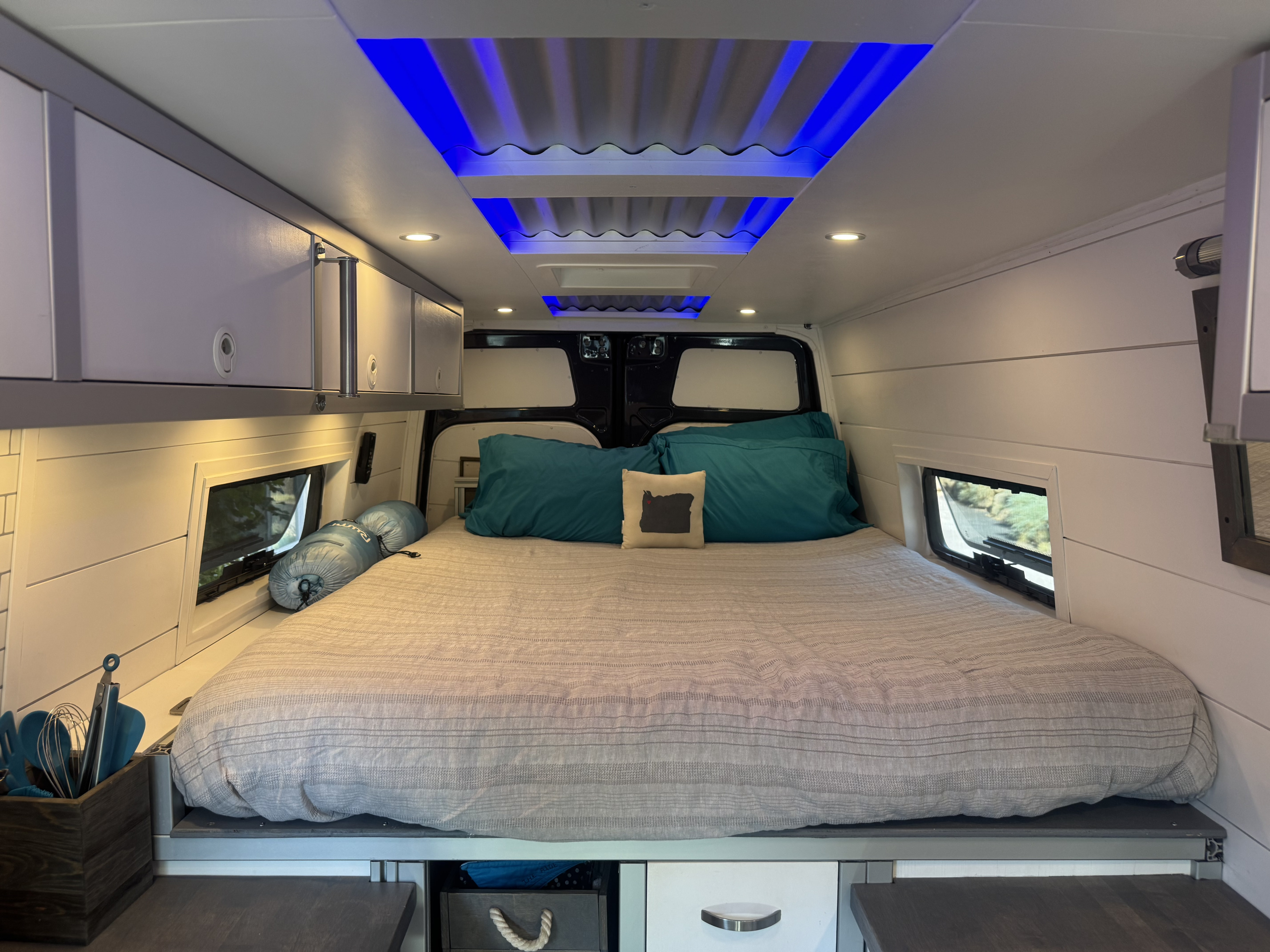 Modern RV rental interior with a comfy bed, sleek storage, ambient blue lighting, and practical windows.. Freightliner Sprinter 2019