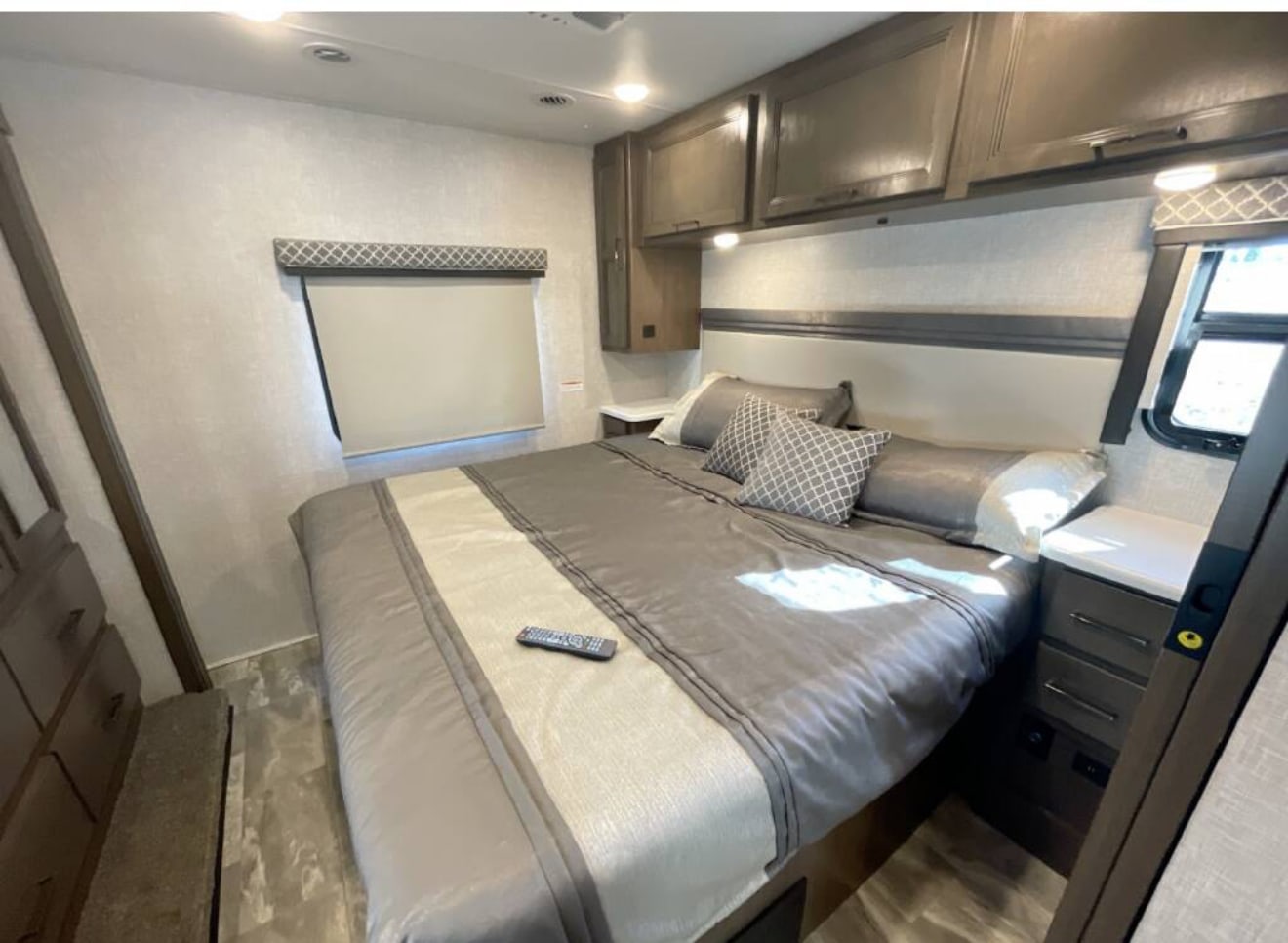 Spacious RV rental bedroom with a comfortable bed, overhead cabinets, and bedside storage. Modern, inviting interior.. Thor Windsport 2022