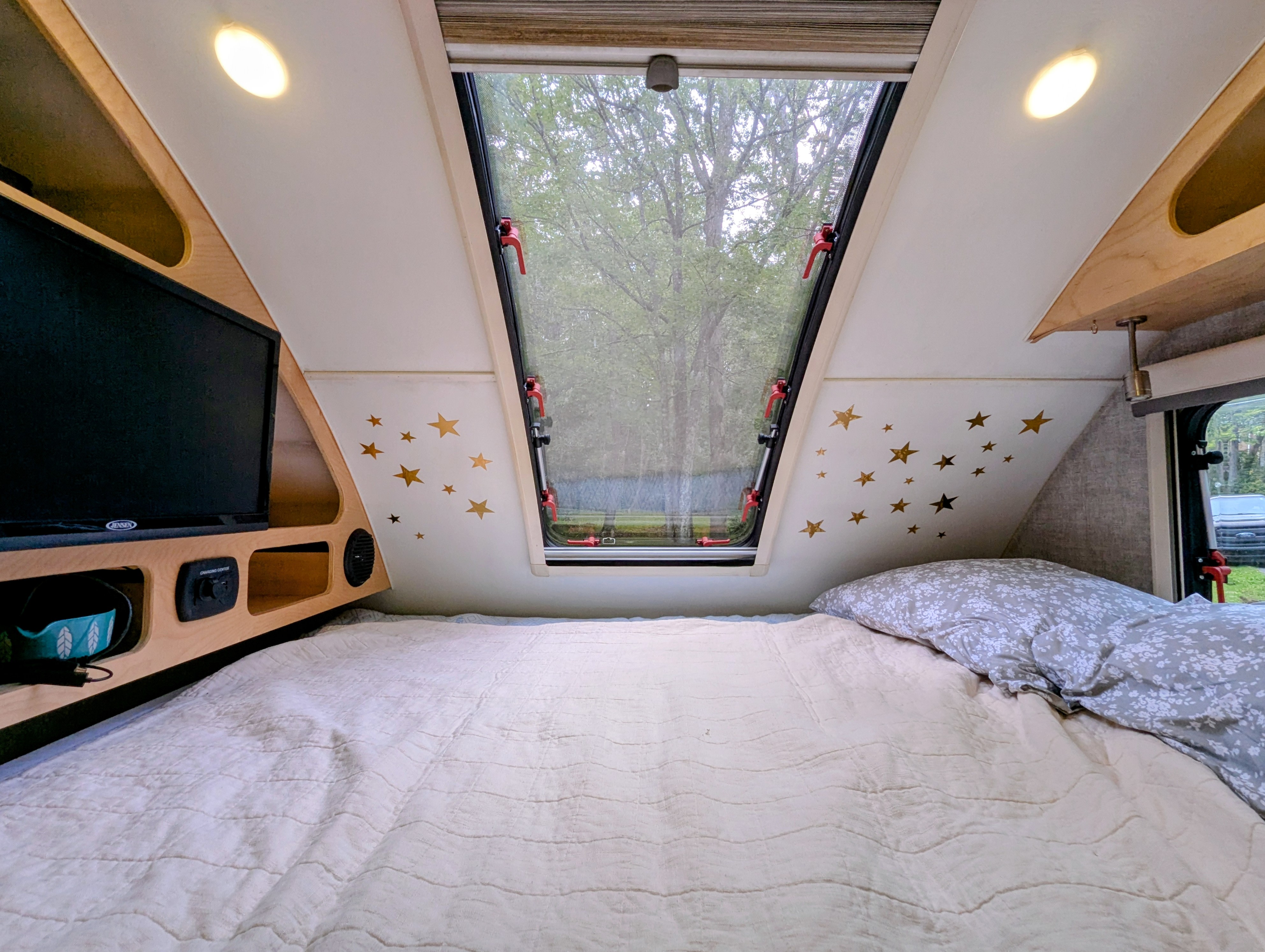 Step into this cozy RV rental bedroom: large window, comfy bed, TV, and charming star wall decals.. Xtreme Outdoors Little Guy Max 2021