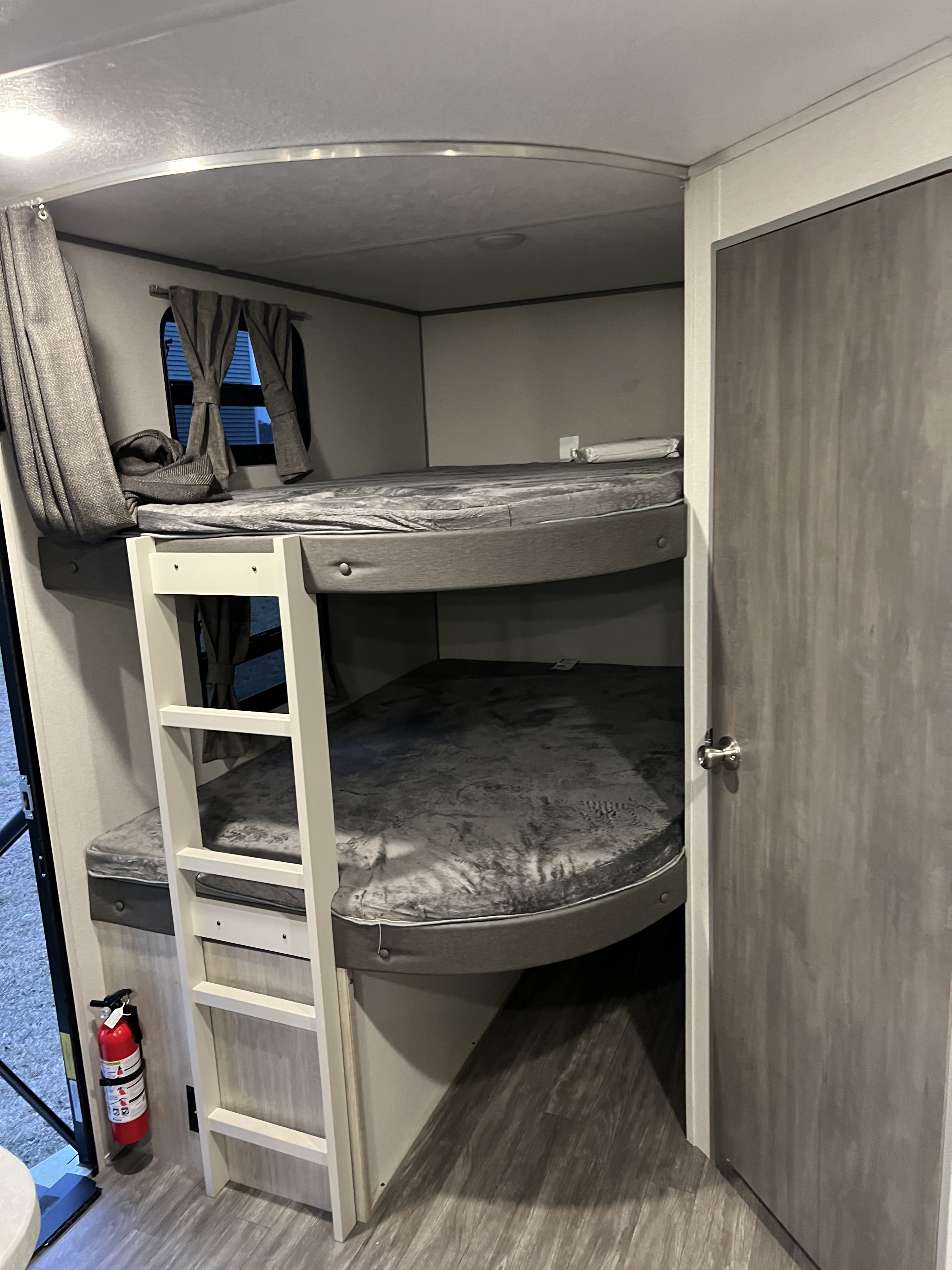 RV rental interior featuring cozy bunk beds, a ladder, windows with curtains, and a fire extinguisher.. Forest River Aurora Aurora 2024