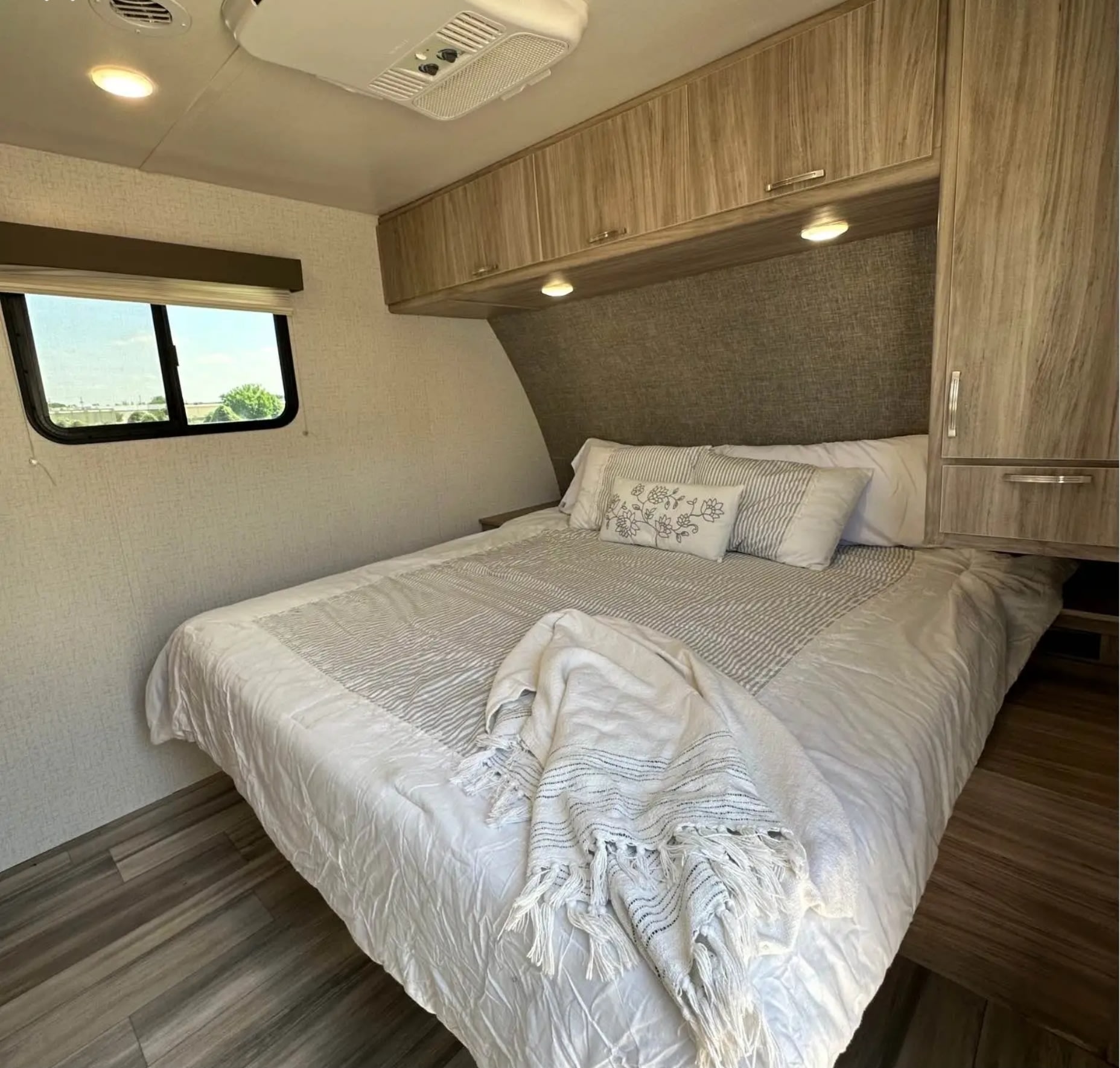 Cozy RV rental bedroom with comfortable bed, overhead storage, and window. Perfect for your next adventure.. Minnie Minnie Trailer 2022