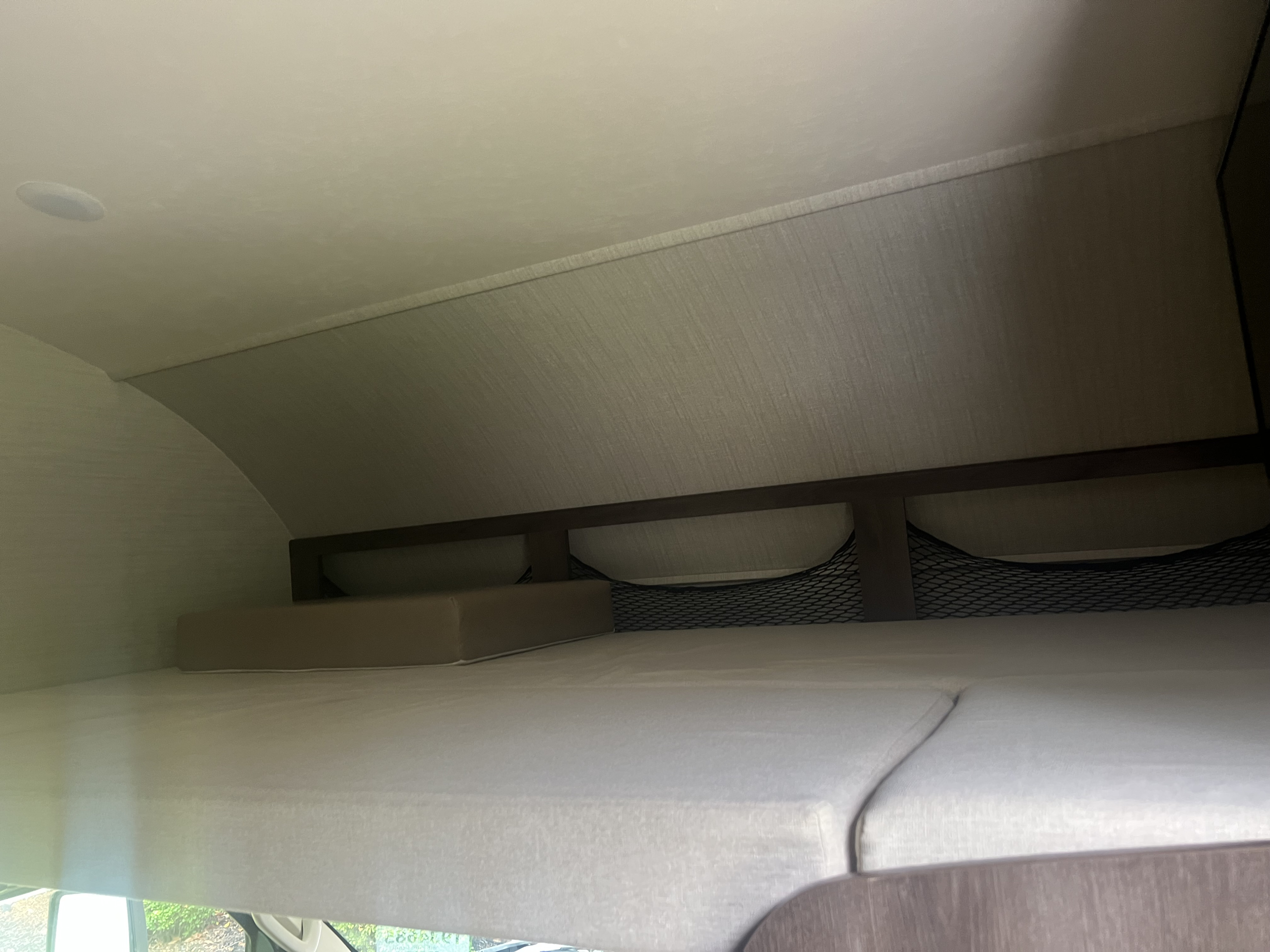 Inside an RV rental: a comfortable bunk bed sleeping area with overhead storage nets and recessed lighting.. Jayco Greyhawk 2018