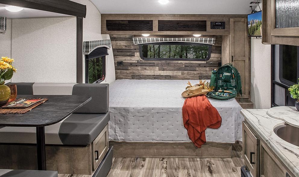 Modern RV rental interior: bedroom, dinette, and compact kitchen. Ideal for road trips and adventurous living.. Sonic Lite 2023