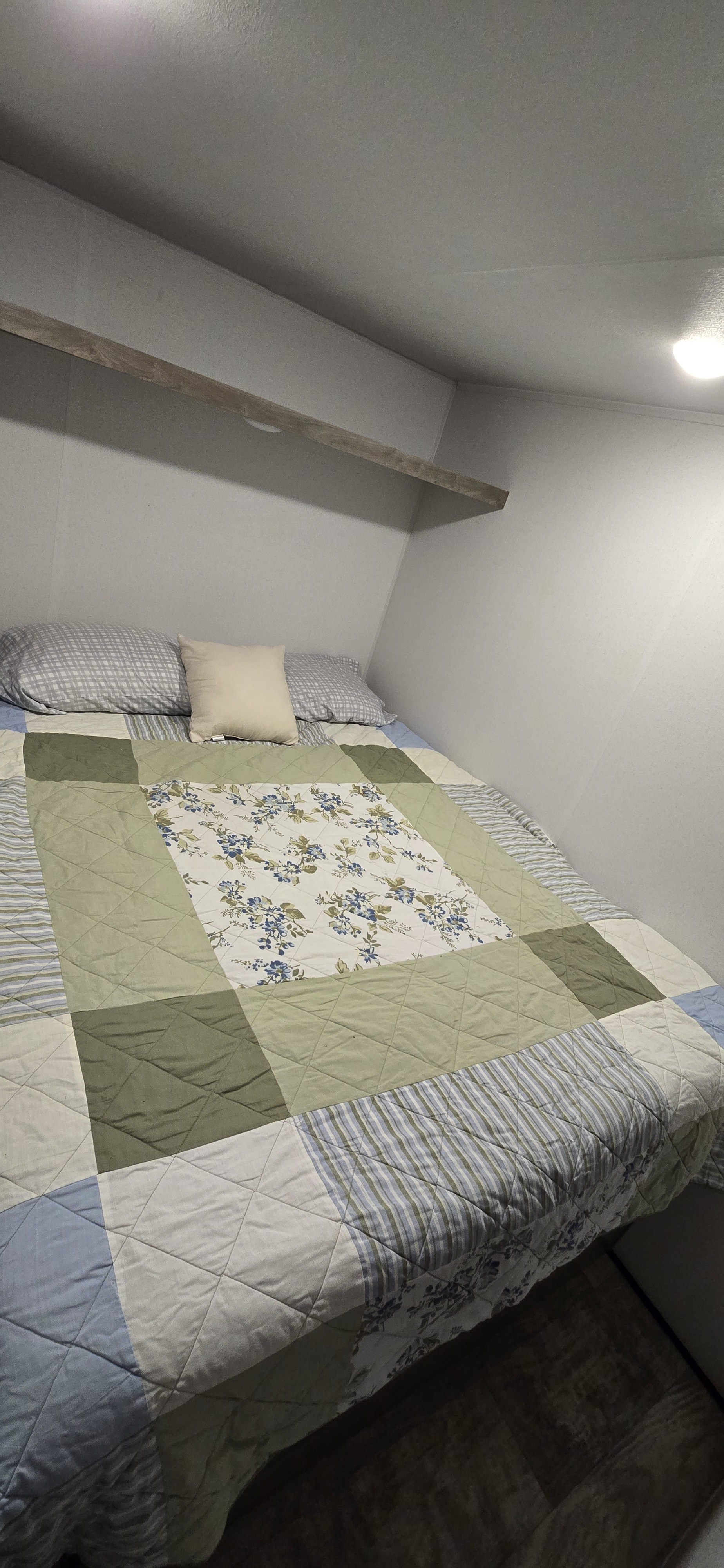 Cozy RV rental bedroom with a patchwork quilt, pillows, and overhead shelf, offering a comfortable RV interior.. Forest River Puma by Palomino 28bhss-2b 2025