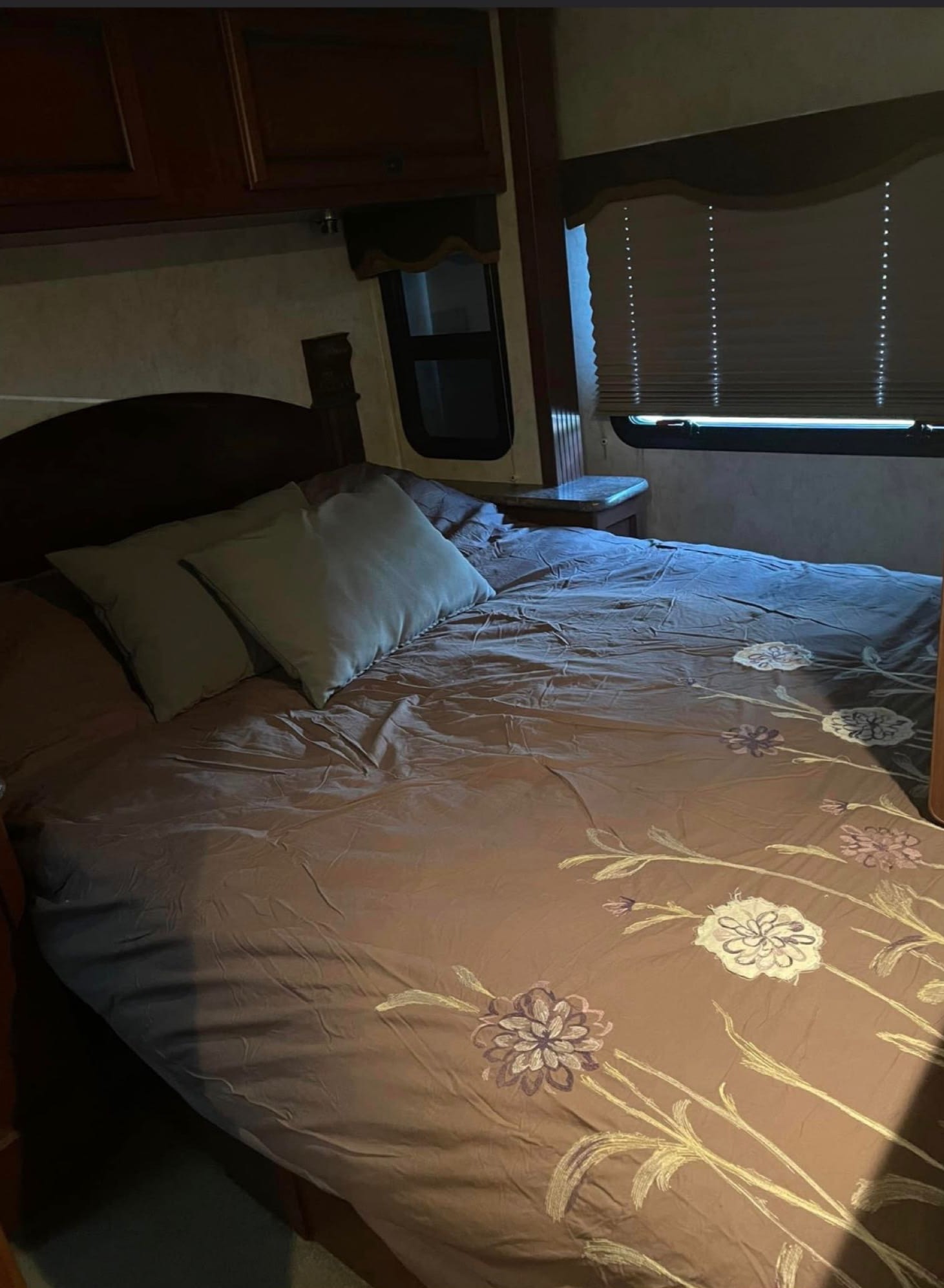 Comfortable RV rental bedroom featuring a bed with a floral comforter, overhead cabinets, and window blinds. Ideal for travel.. Tioga Ranger 2011