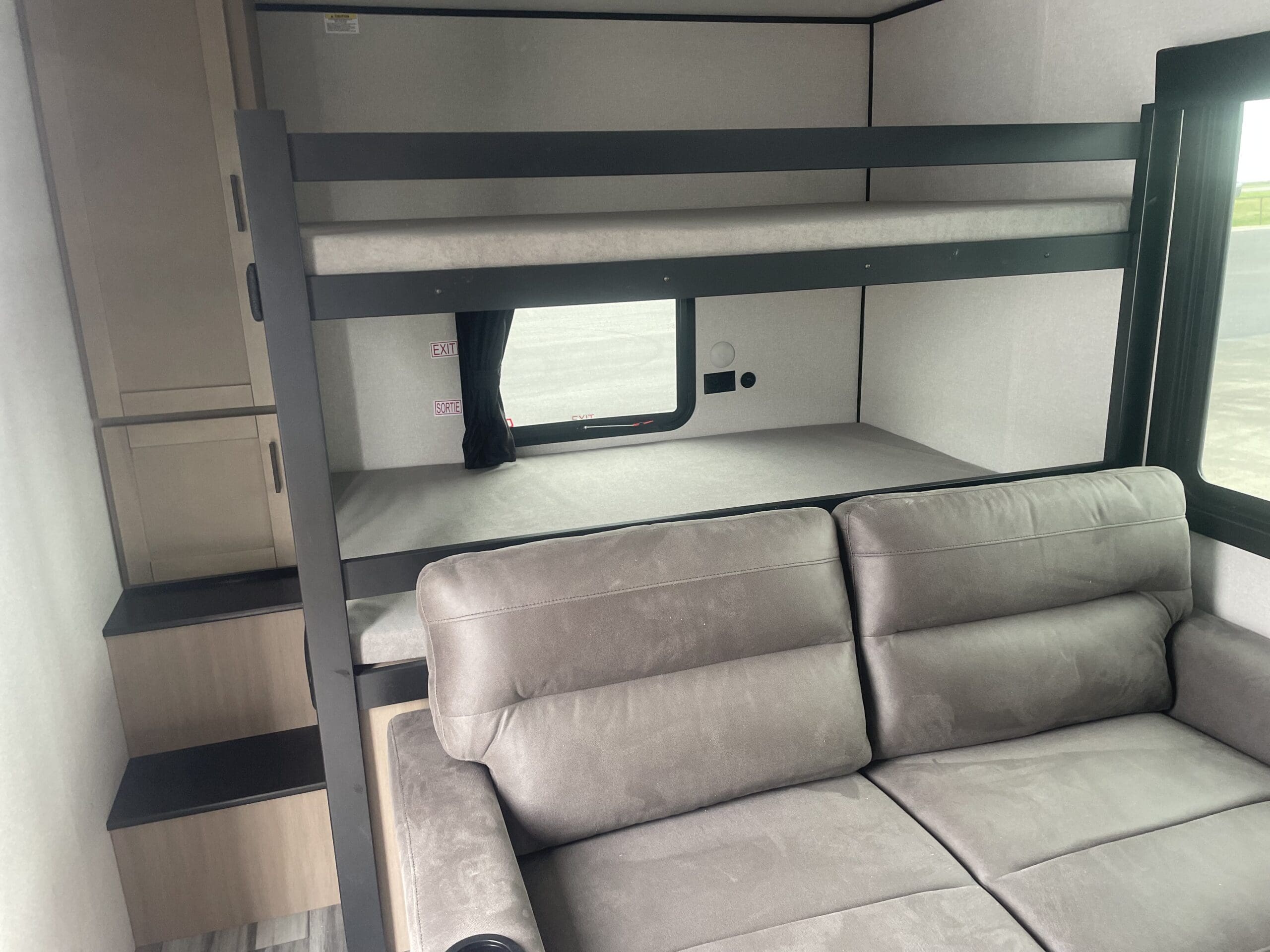 This RV rental interior features modern bunk beds, a cozy gray couch, and integrated storage, ideal for family trips.. Jayco SLX 287BHSW 2026