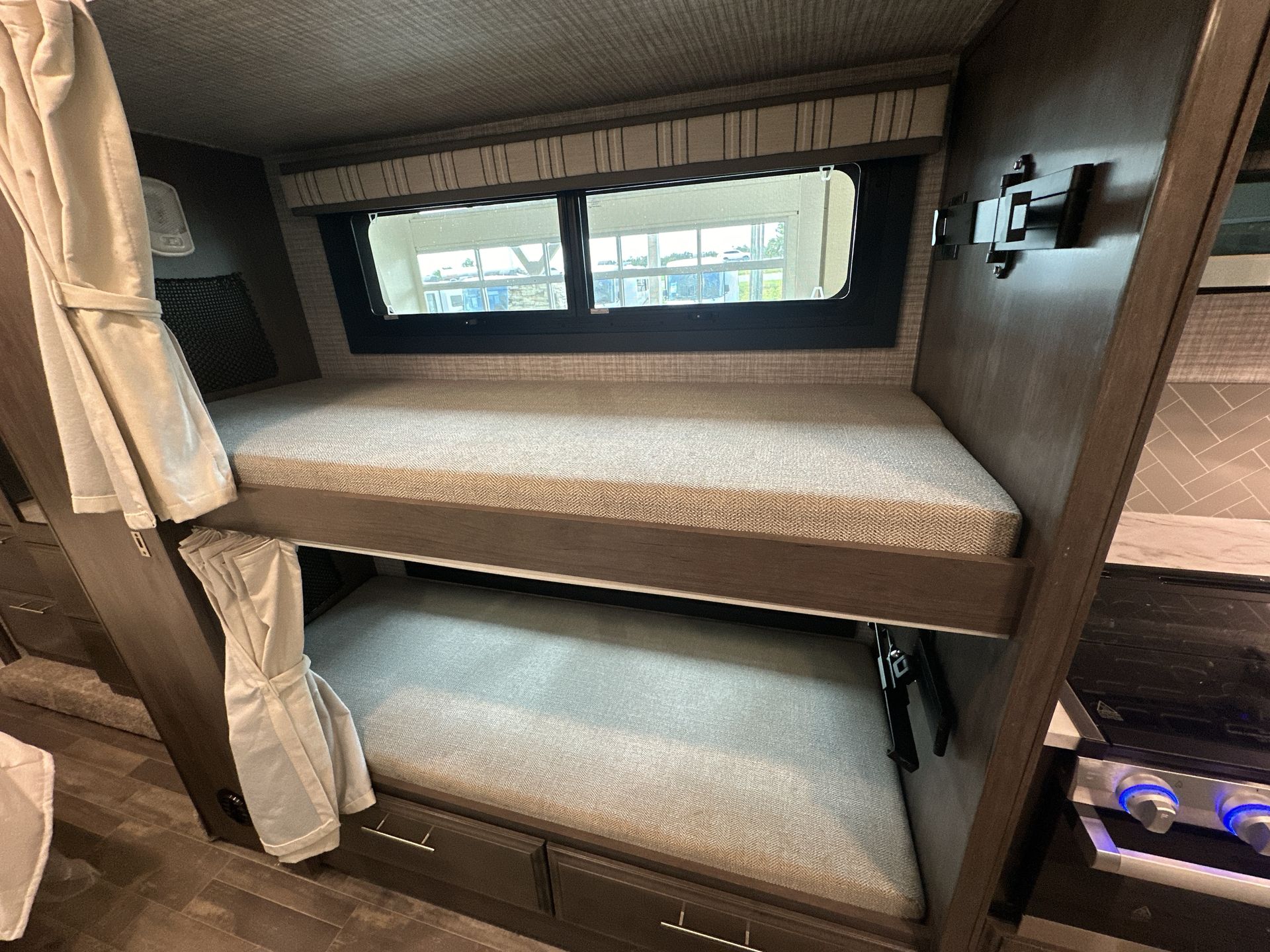 This RV rental features cozy bunk beds with a window, privacy curtains, and storage drawers, ideal for compact sleeping.. Jayco Greyhawk 31F 2025