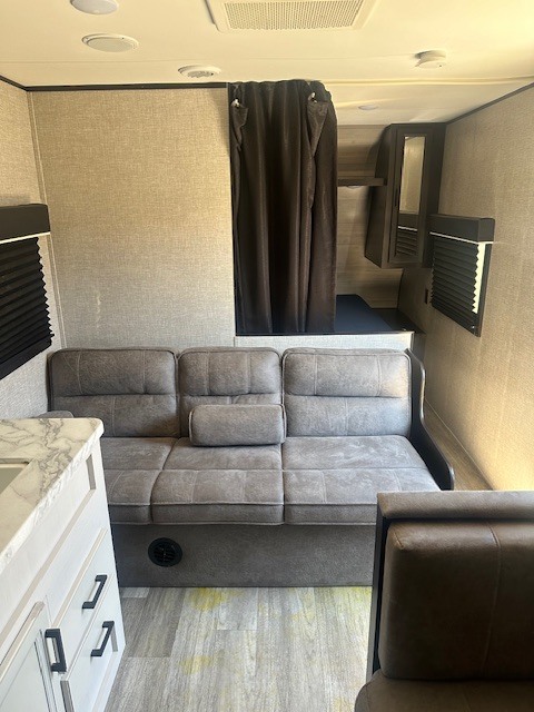 This RV rental interior features a cozy convertible sofa, kitchen counter, and private bunk area for a comfortable journey.. Jayco Jay Flight SLX 2022