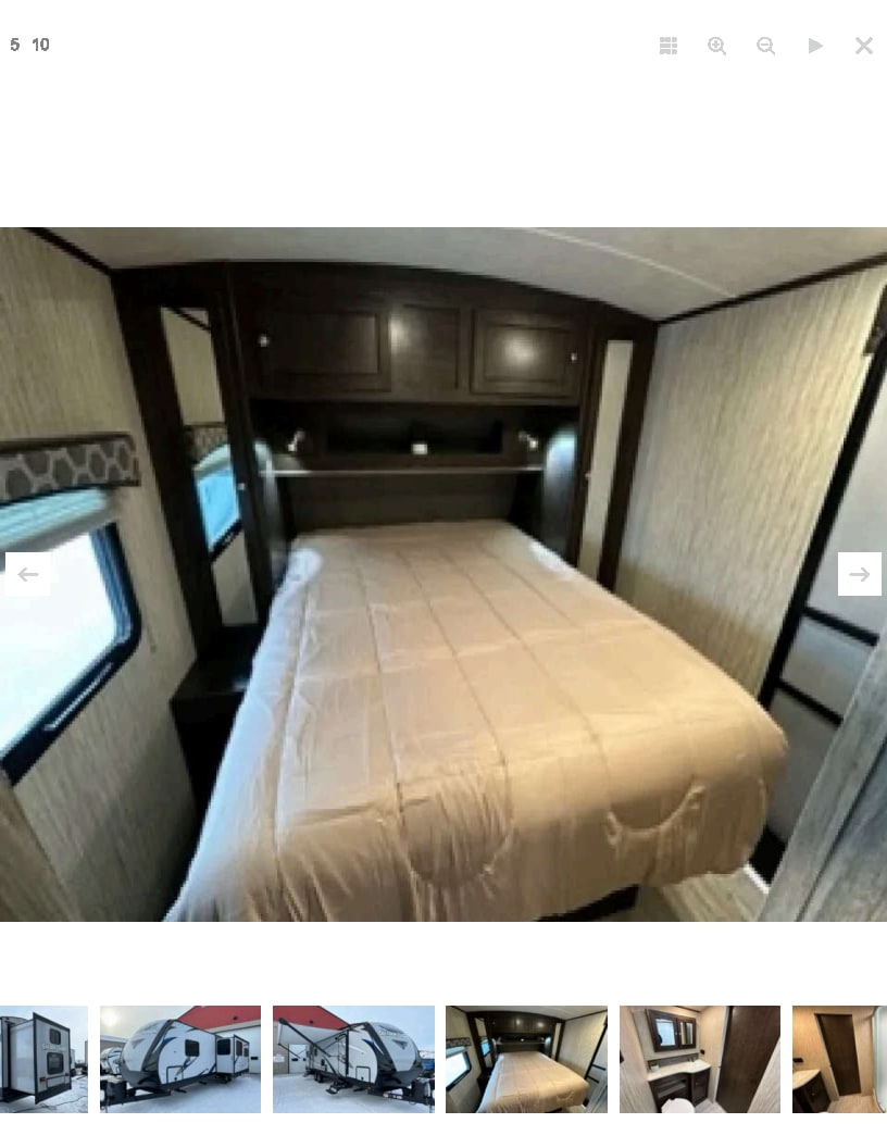 Cozy RV rental bedroom featuring a large bed, overhead storage cabinets, and bedside amenities. Perfect for your camper or travel trailer getaway.. Shadow Trailers 289 RBS 2018