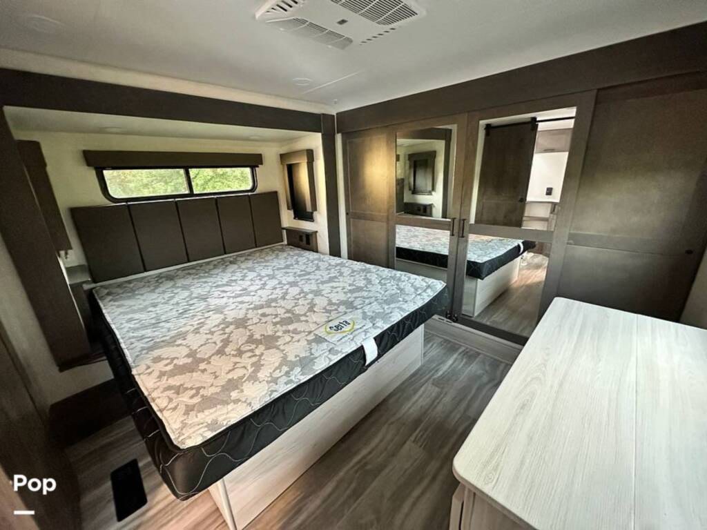 Spacious RV rental bedroom with a large bed, built-in headboard, scenic window, and mirrored wardrobe for ample storage.. Alliance Valor 4013 2022