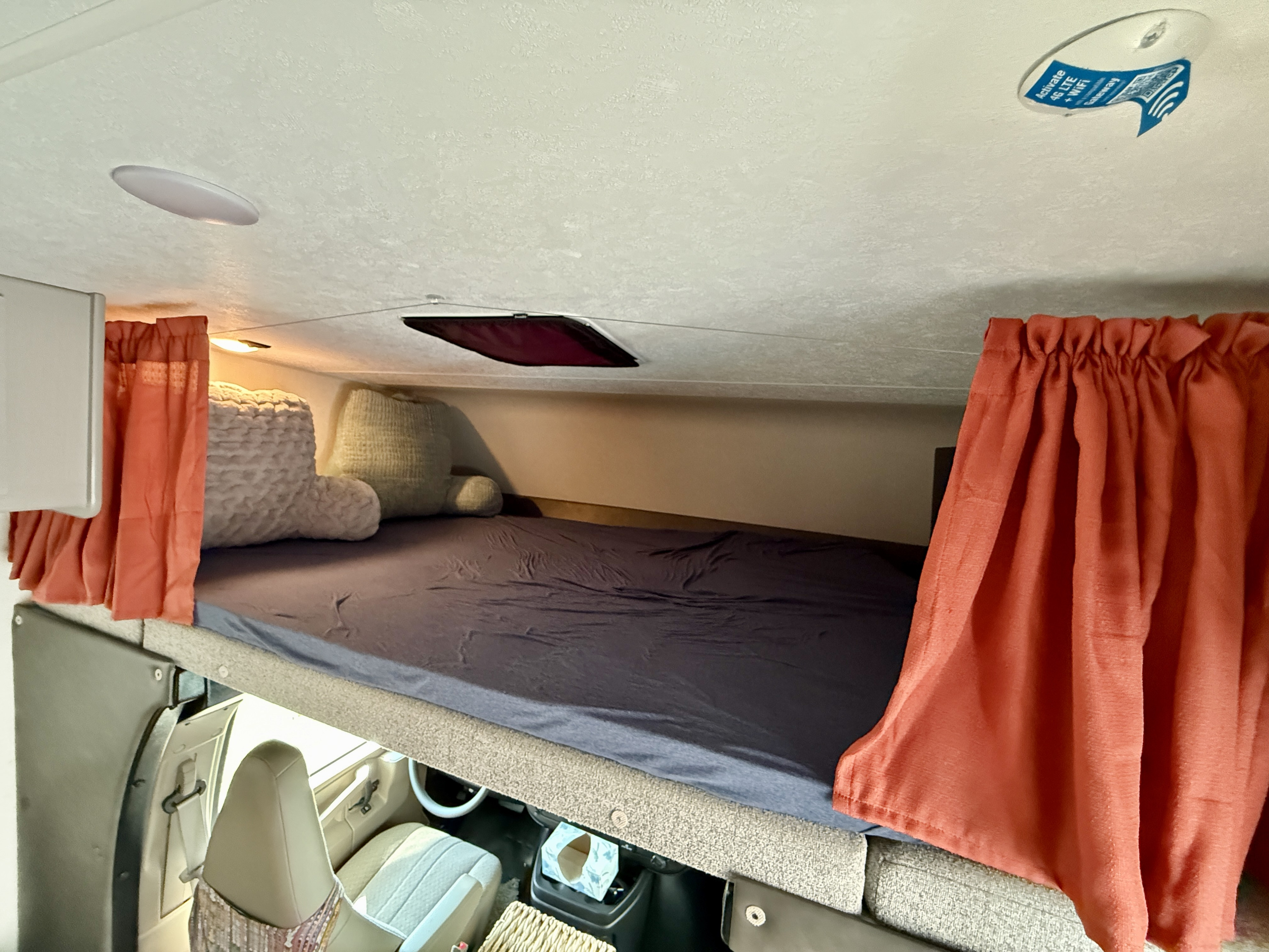 RV rental: Comfy cabover bed, orange privacy curtains, and an overhead WiFi gateway for connectivity.. Forest River Coachman Freelander 21QSS 2025