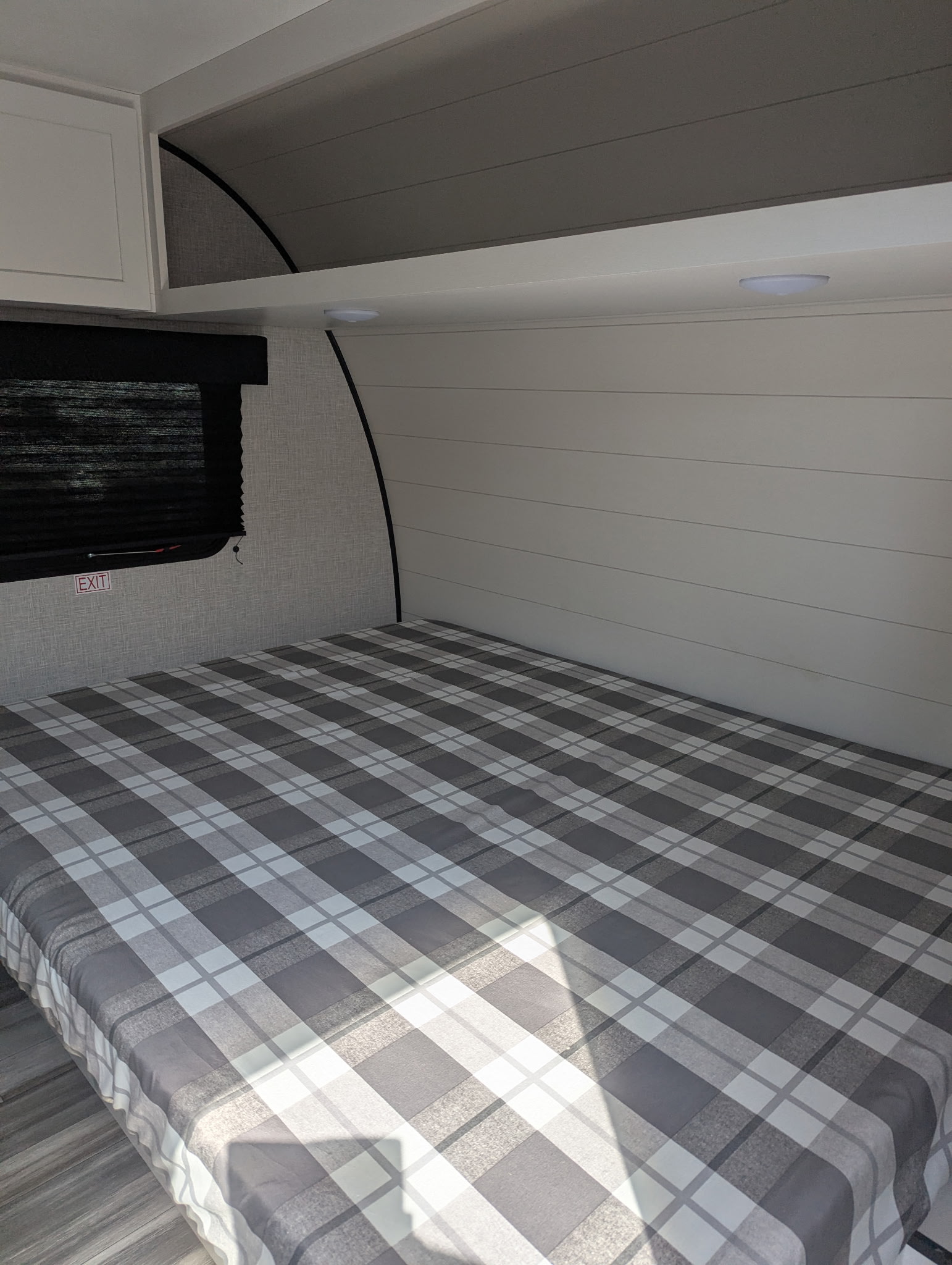 Experience comfort in this modern RV rental bedroom, featuring a cozy grey and white plaid bed and stylish shiplap walls.. Jayco Jay Flight SLX 2025