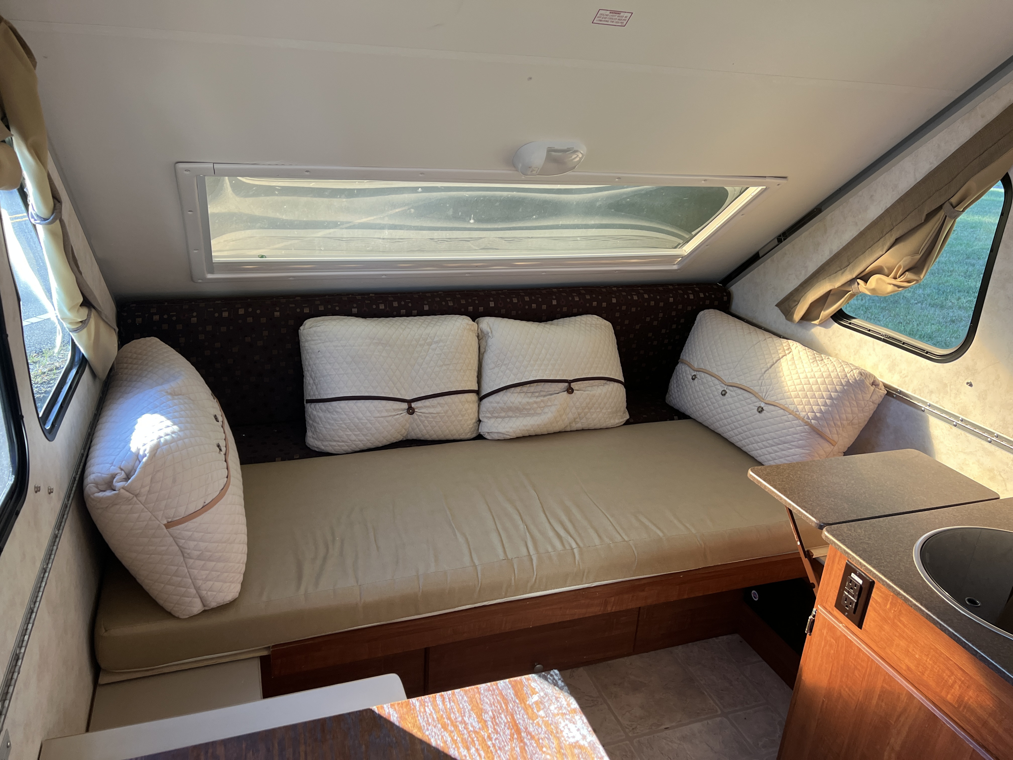 This RV rental interior features a convertible sofa/bed, large window, and kitchenette. Ideal for adventure travel.. A Liner A Liner Popup Trailer 2013