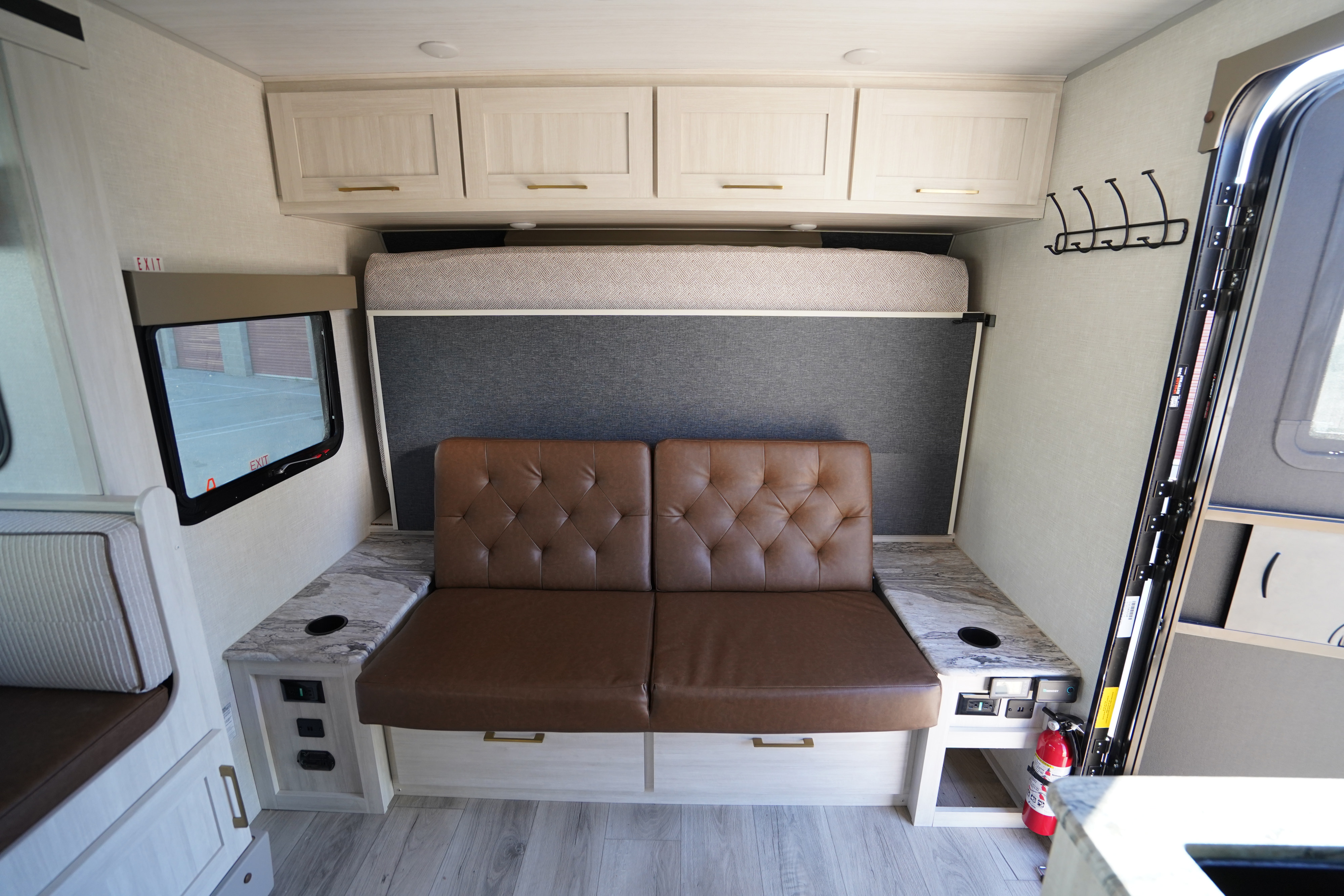 RV rental interior featuring a brown sofa, overhead bunk, marble-look counters, and charging ports for comfort.. Forest River Surveyor Legend 2024