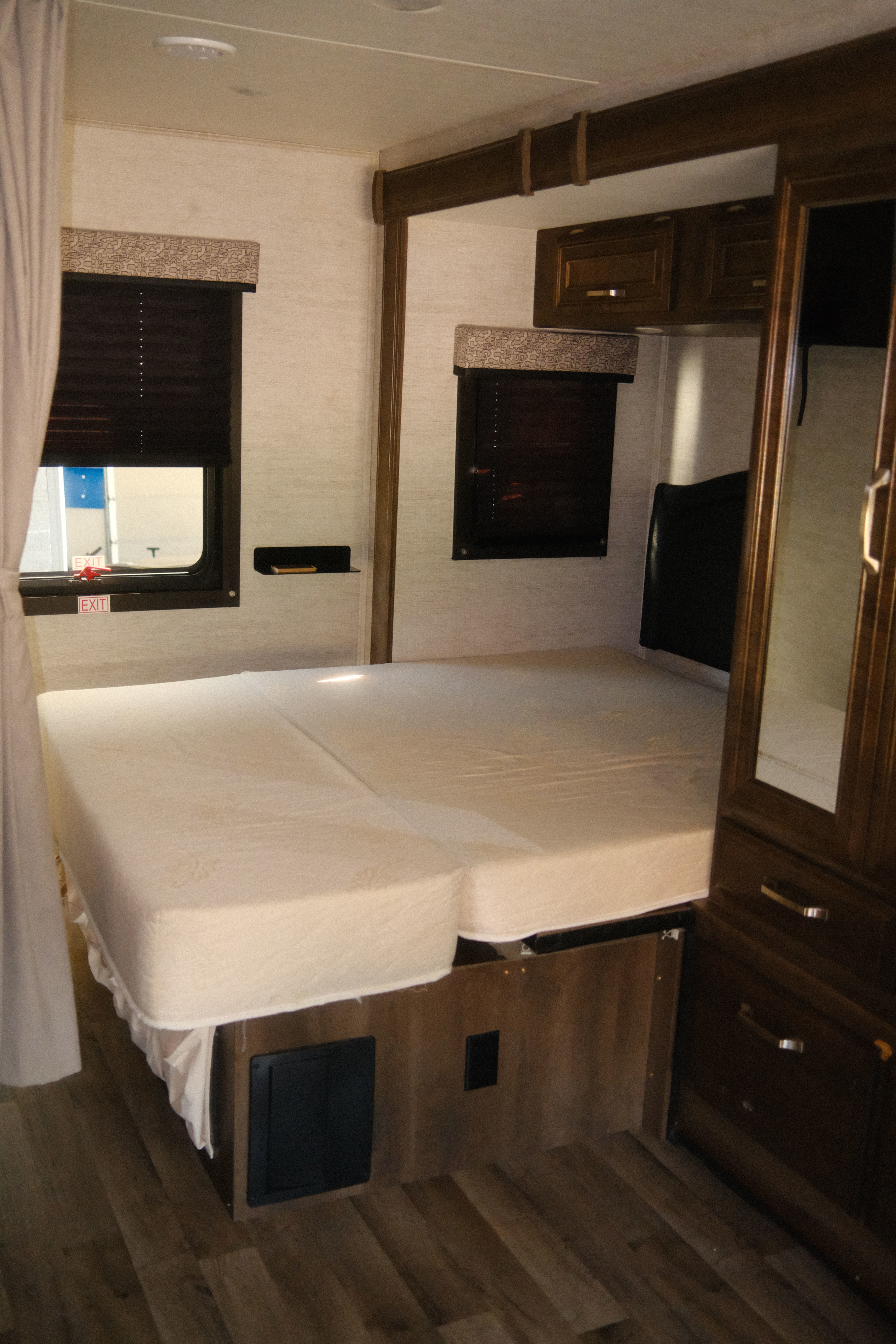 RV rental interior: A compact bedroom with a divided mattress, windows, storage cabinets, and a mirrored wardrobe.. Jayco Melbourne Prestige 2021