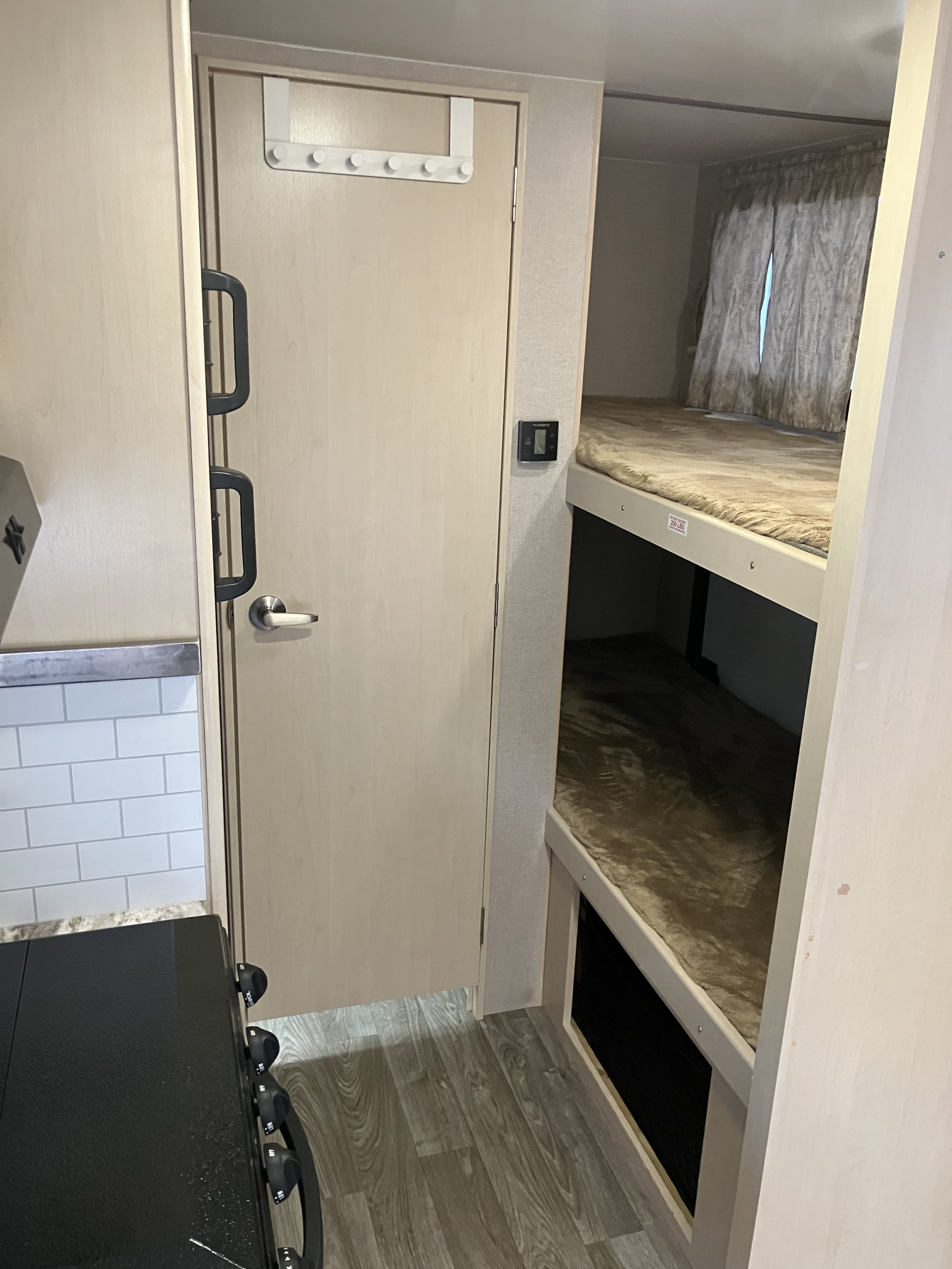 RV rental interior showcasing cozy bunk beds, a functional kitchen space, and a door, perfect for travel adventures.. Winnebago 2100BH 2019
