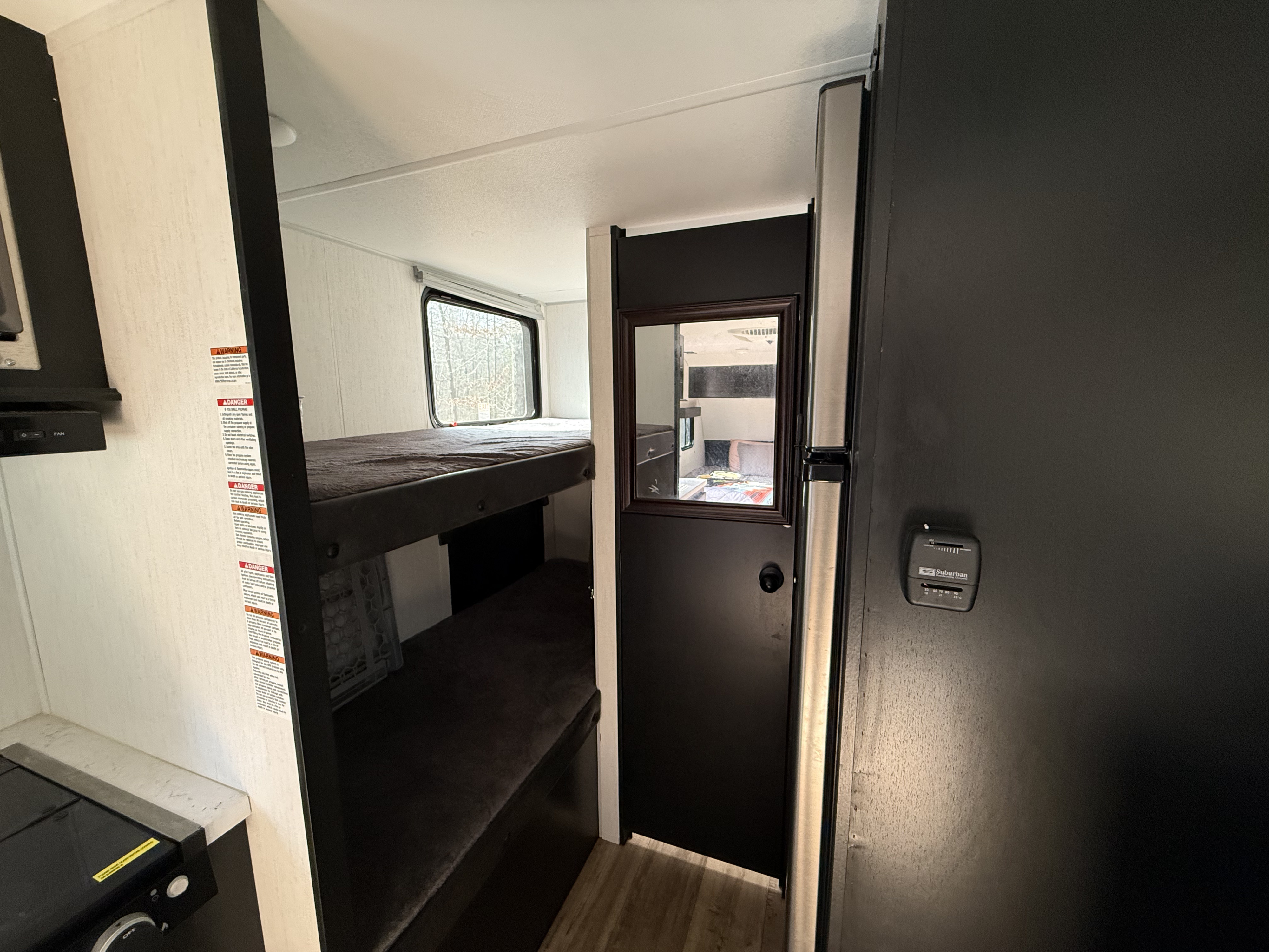 Inside this RV rental: dark bunk beds, a compact kitchen on the left, and a thermostat on the right wall.. Forest River Cherokee Wolf Pup 2022