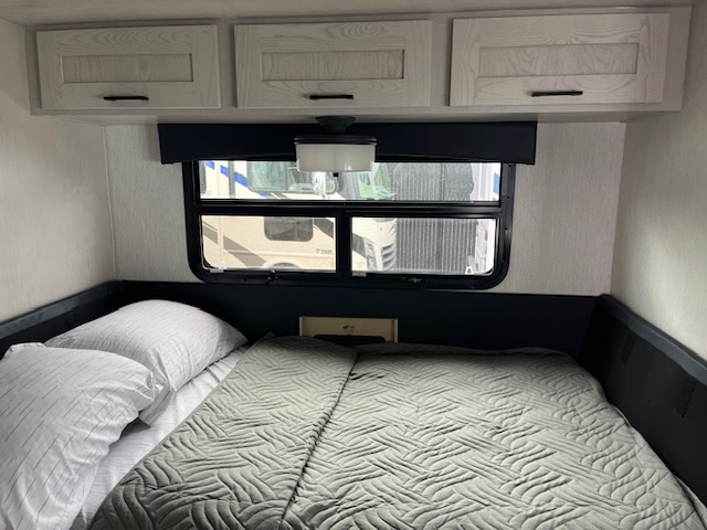 Inside a modern RV rental: comfortable bed with pillows, overhead storage cabinets, and a window for natural light.. Nexus Viper 2026
