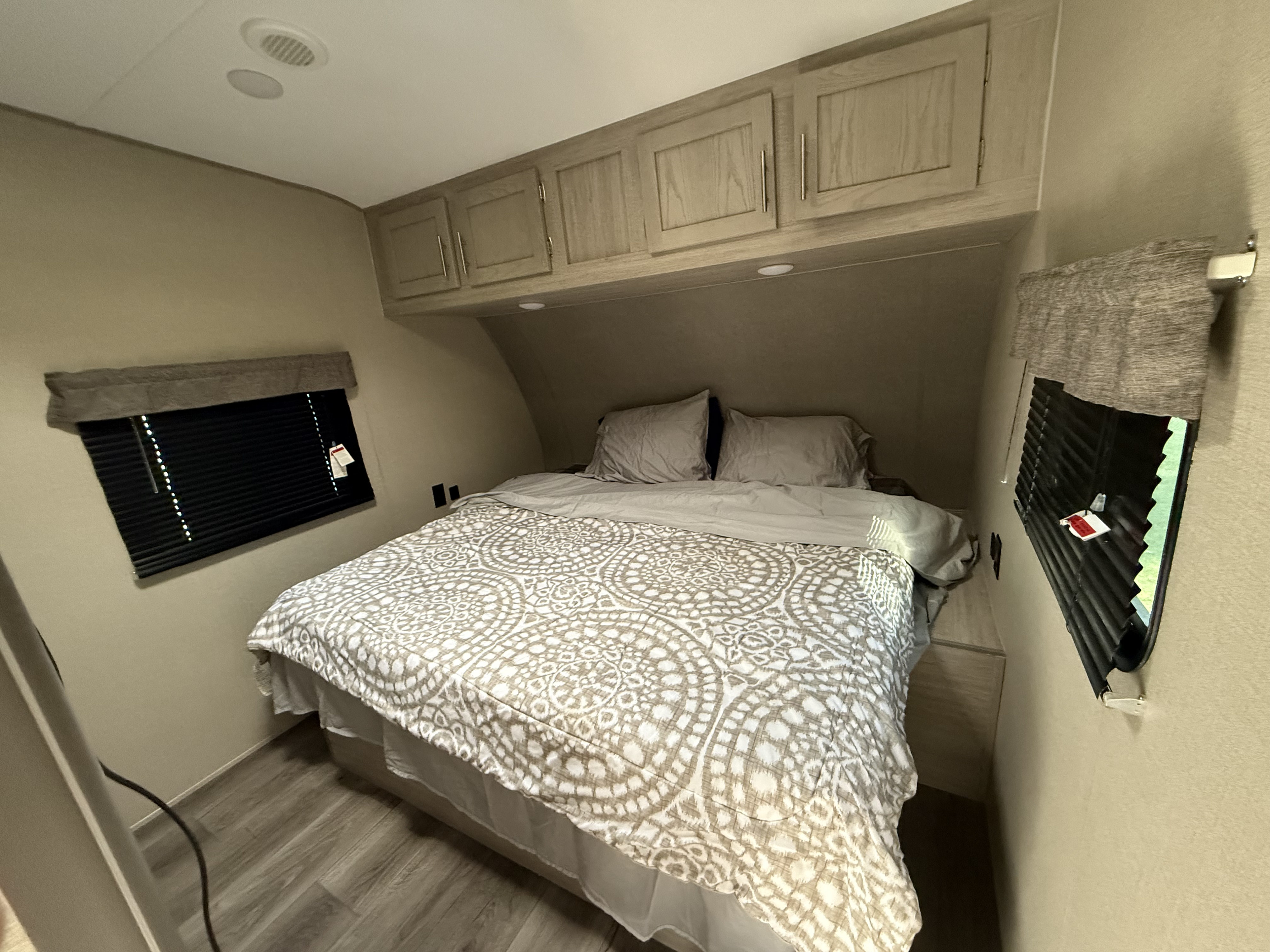 Cozy RV rental bedroom with a comfy bed, overhead cabinets, and windows, perfect for your next adventure.. Coachmen Catalina 2022