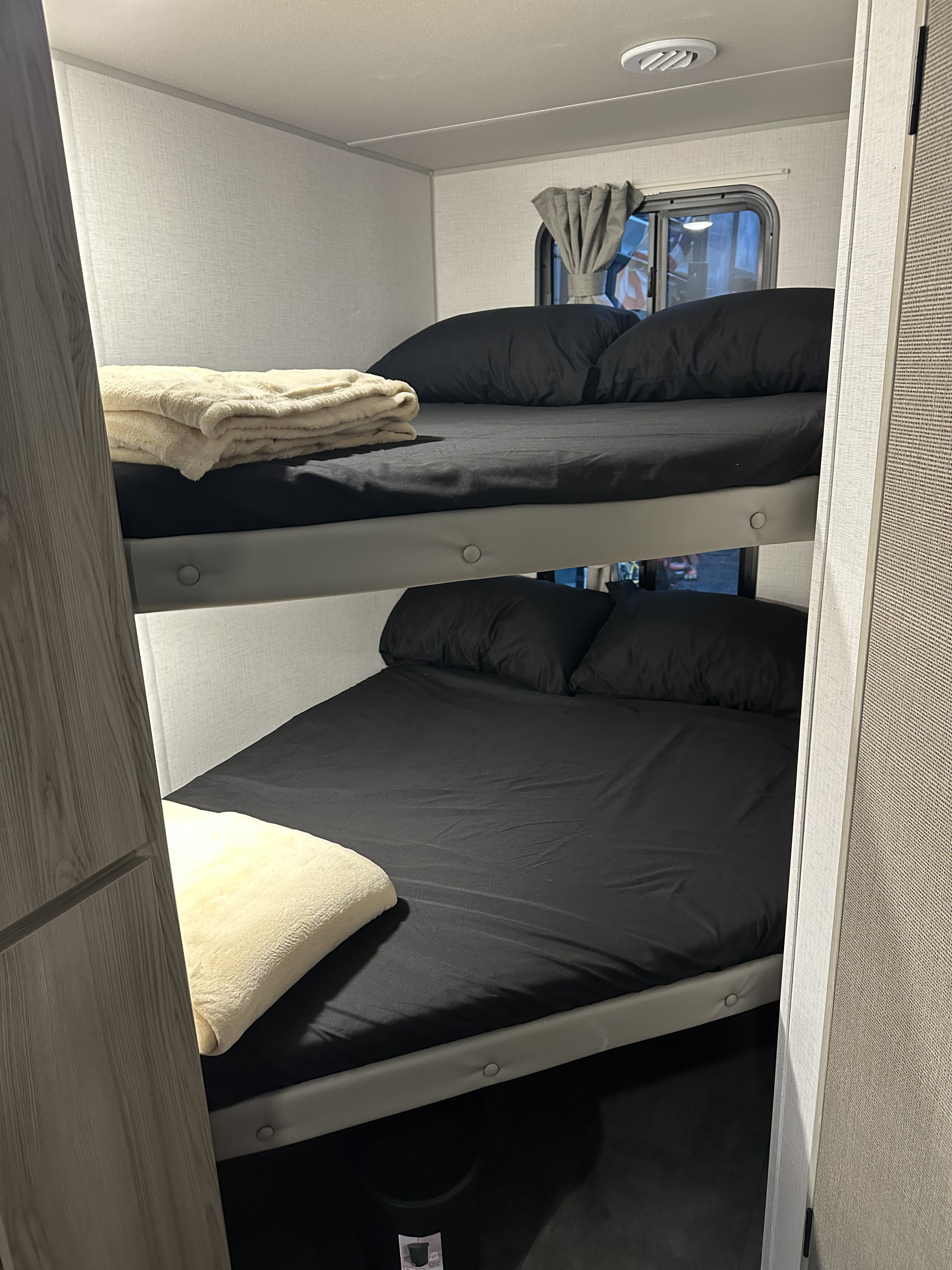 Cozy bunk beds inside an rv rental, featuring black sheets and pillows, ideal for a comfortable family getaway.. Forest River Salem Cruise Lite 2024