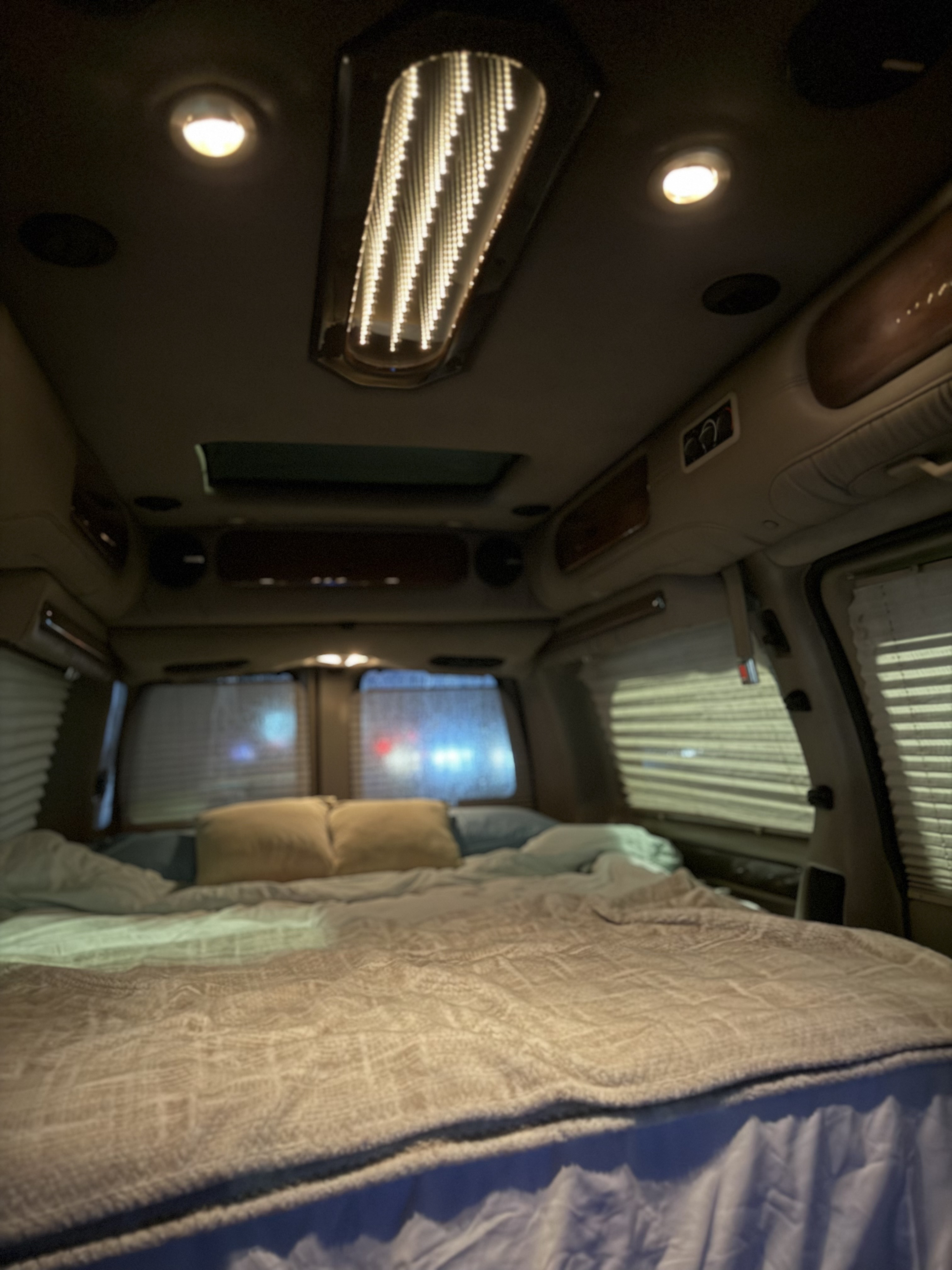 Cozy interior of an **rv rental** at night, featuring a comfortable bed, warm lighting, and window blinds. Perfect for travel.. Chevrolet Express Explorer AWD 2007