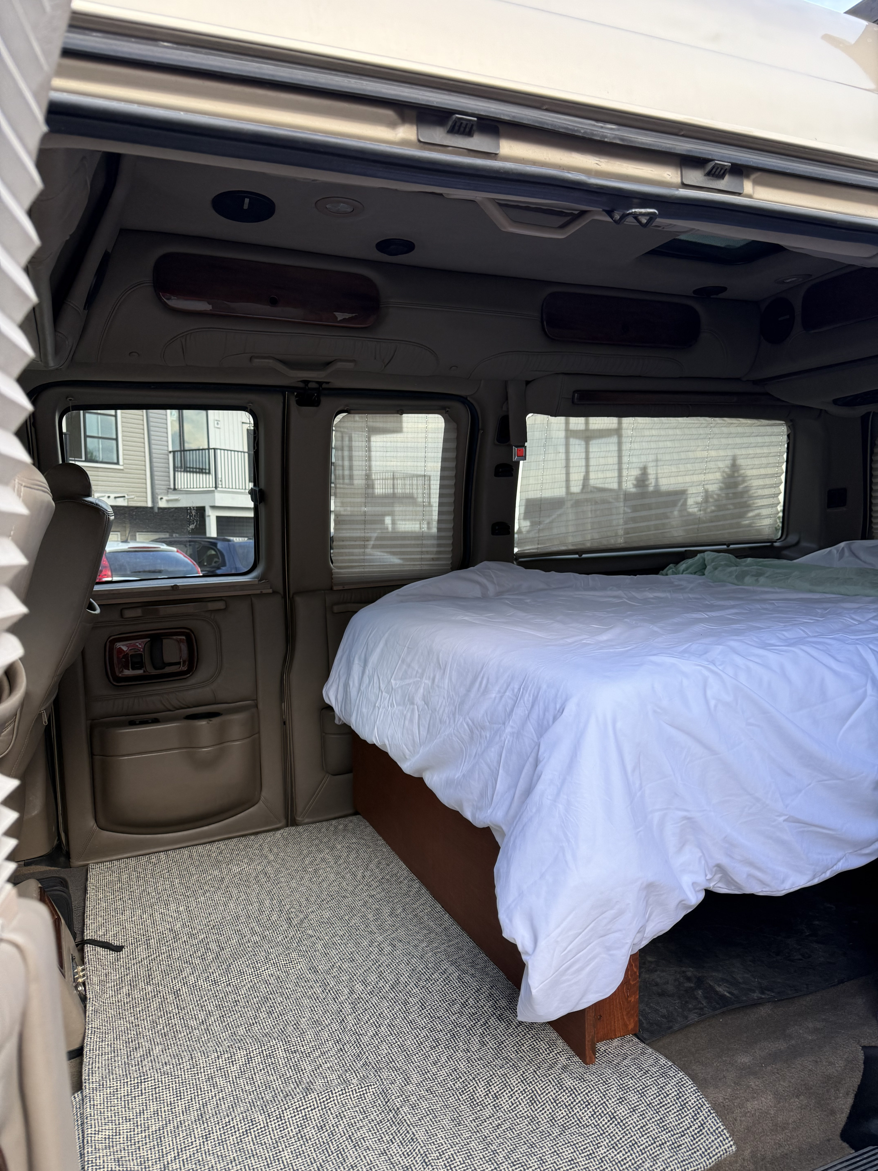Van life setup: This RV rental showcases a comfortable bed, woven floor mat, and window shades, ready for your next adventure.. Chevrolet Express Explorer AWD 2007