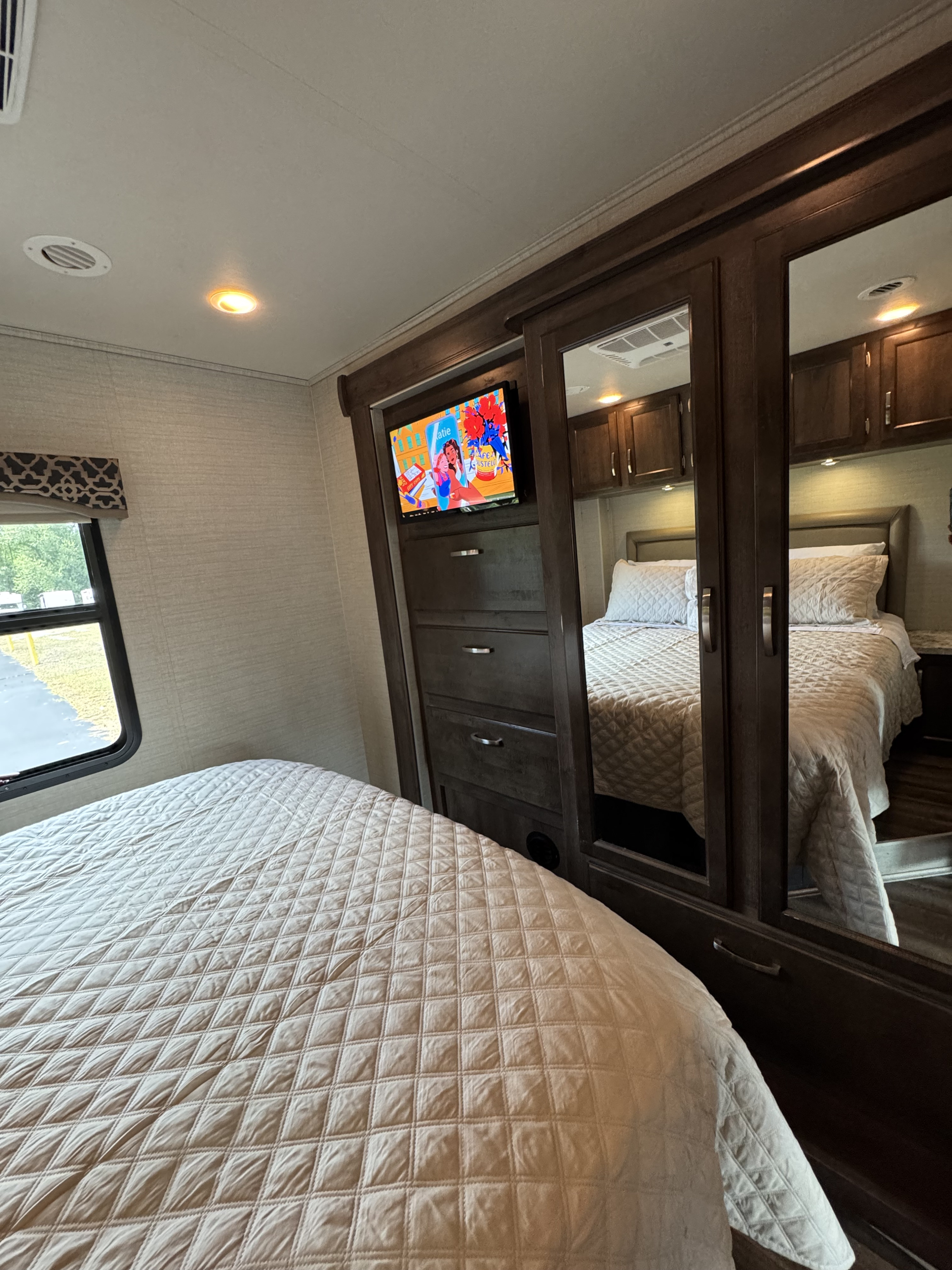 Cozy RV rental bedroom: quilted bed, TV, and mirrored cabinet making the compact space feel larger.. Jayco Alante 2019