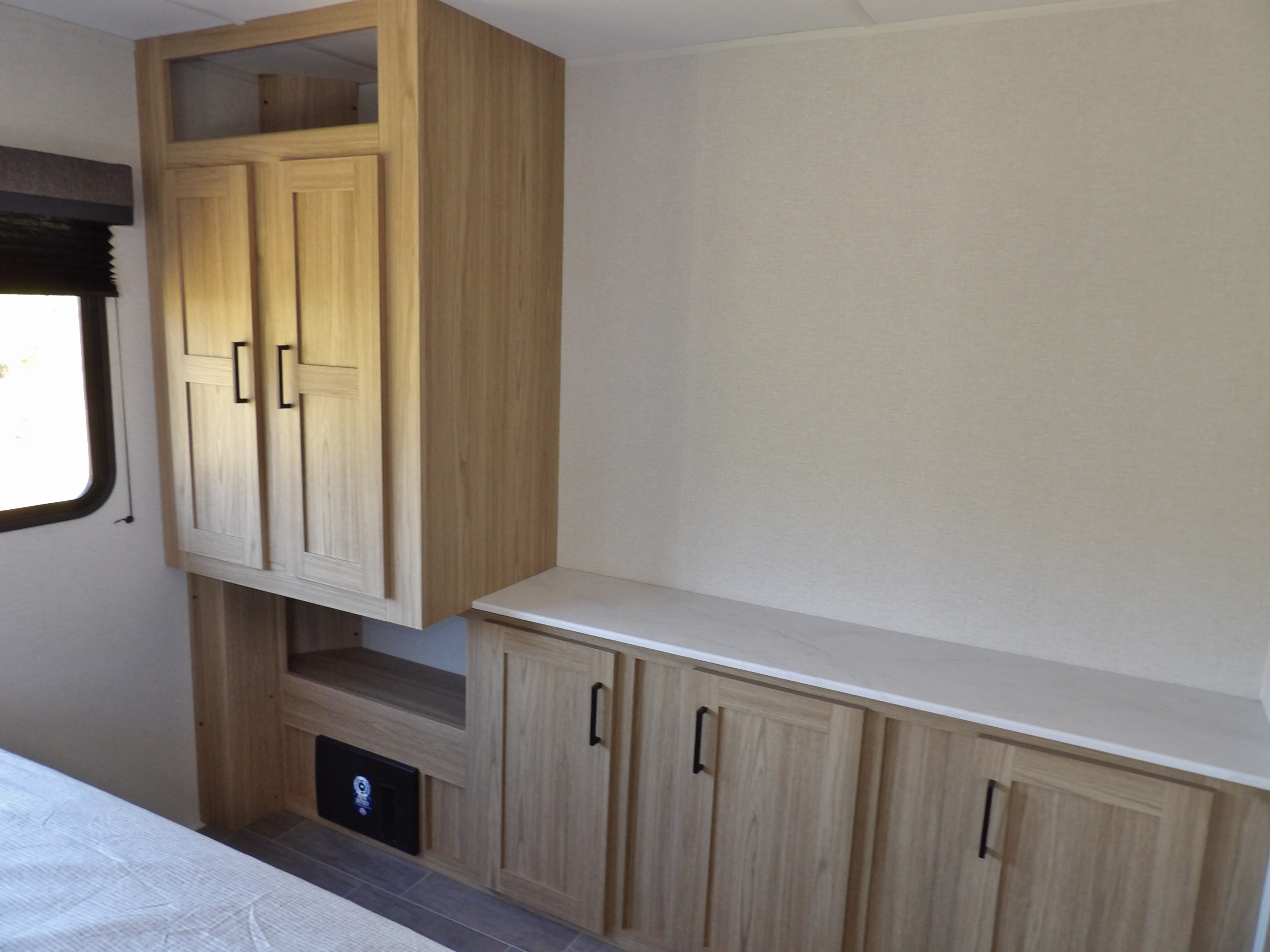 RV rental bedroom interior featuring light wood cabinetry: a tall wardrobe & lower storage with a white counter.. Other Other 2025