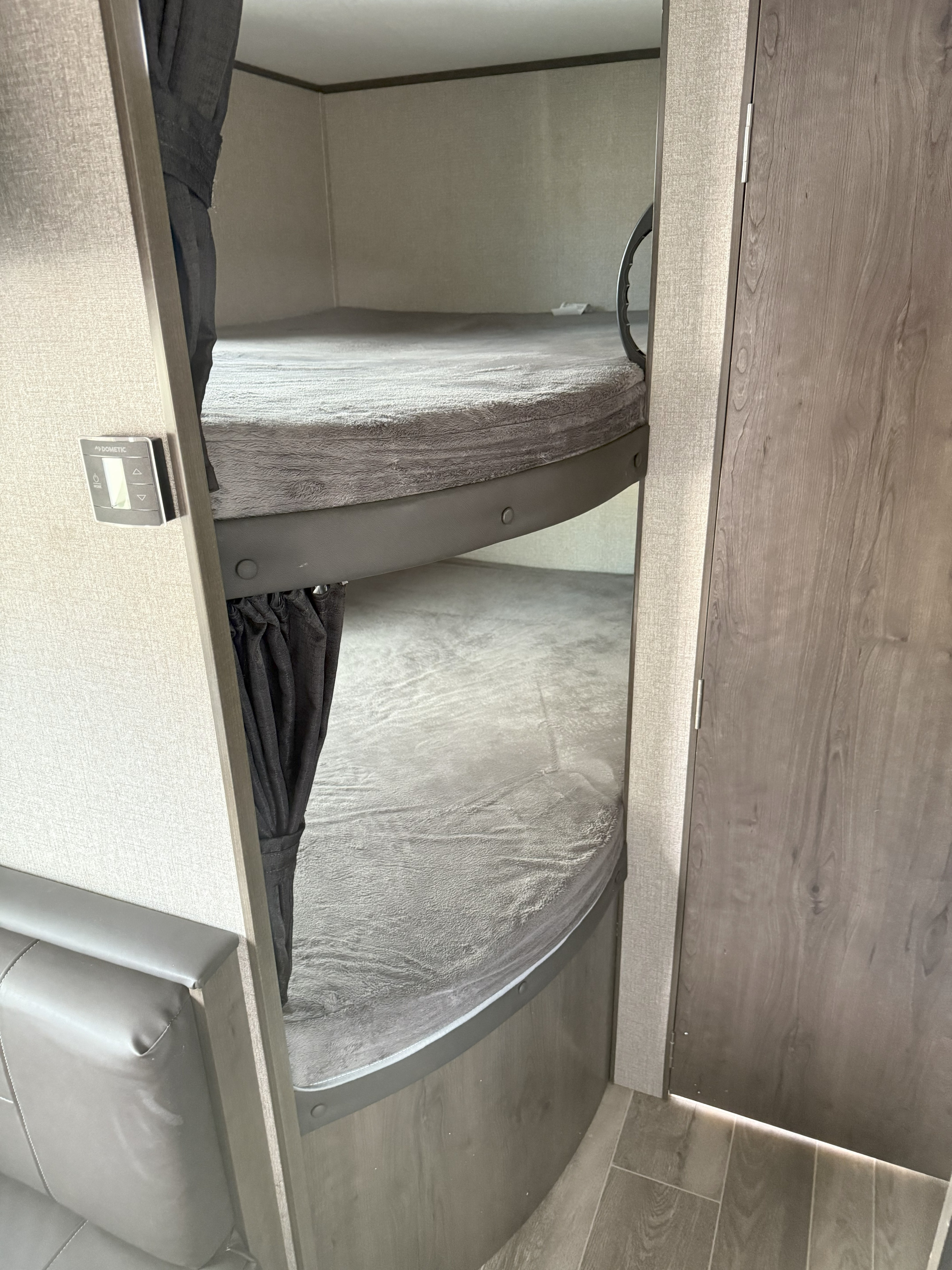 Cozy bunk beds in an RV rental, featuring grey mattresses, curved frames, and Dometic controls.. Jayco Jay Flight 2021
