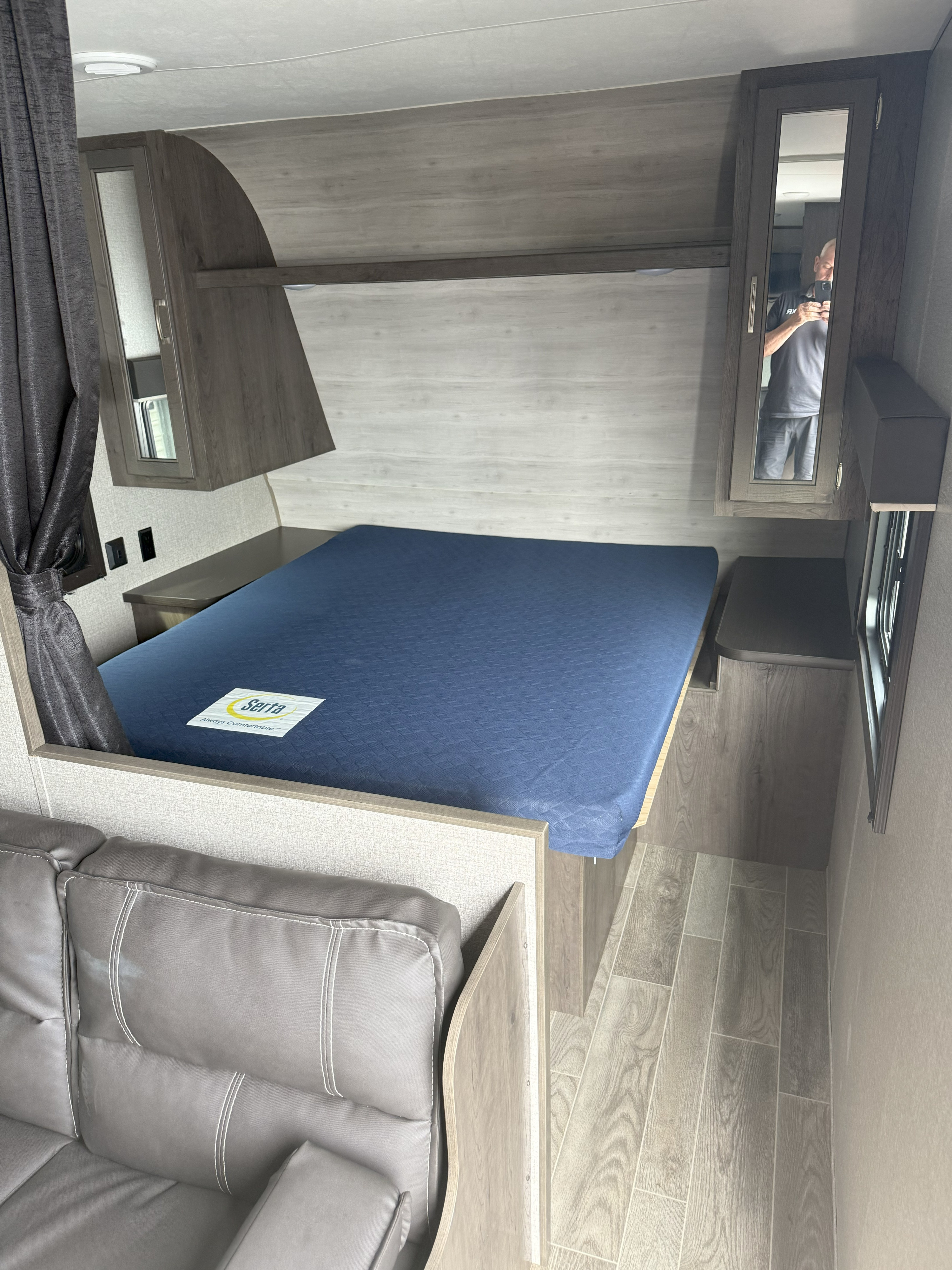 Compact RV rental bedroom featuring a comfy Serta bed, built-in cabinets, and a gray sofa for relaxing.. Jayco Jay Flight 2021