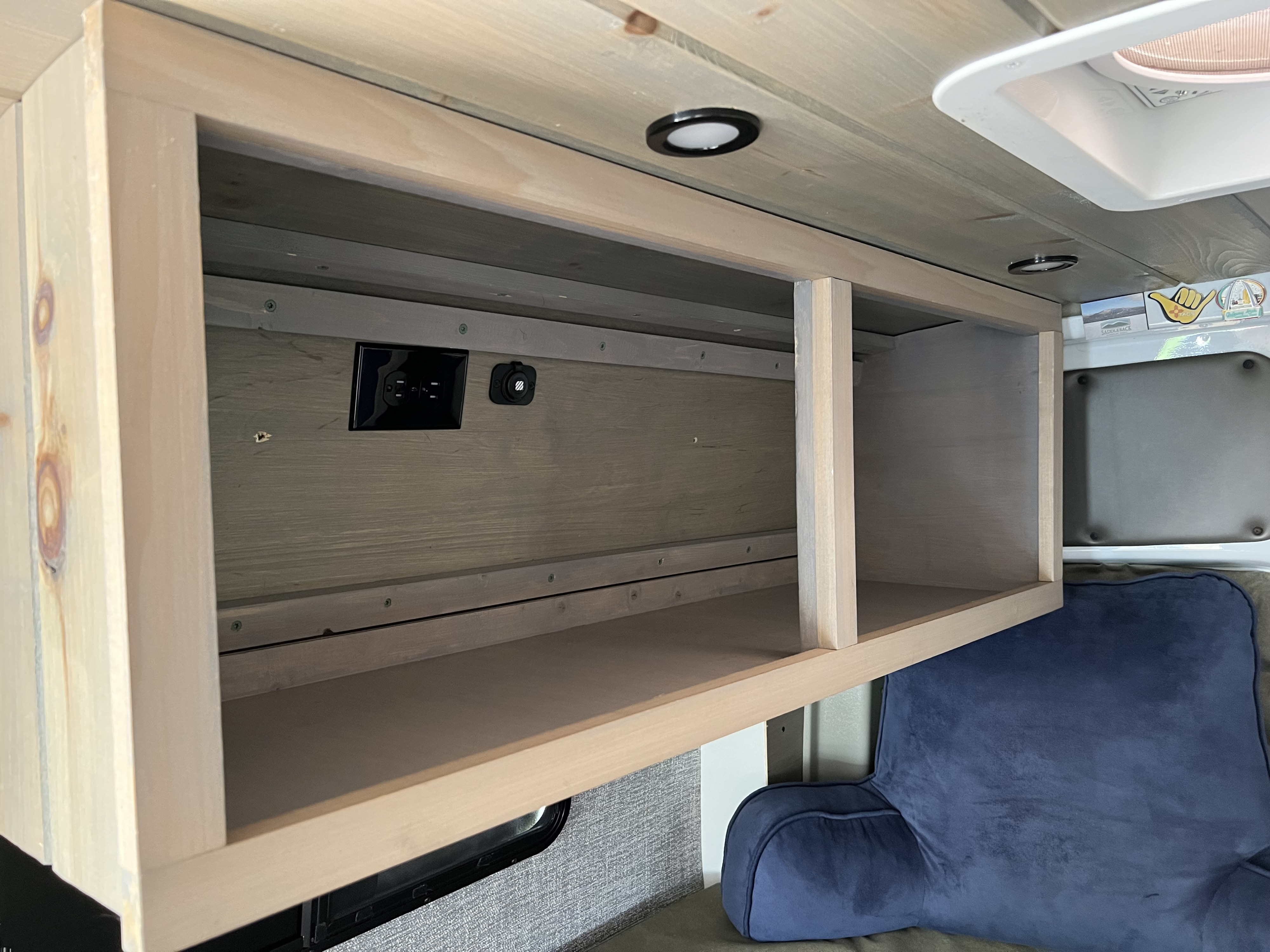 Inside this RV rental, a custom wood overhead cabinet offers convenient storage with AC and USB outlets, brightened by ceiling lights.. Mercedes Sprinter 2011