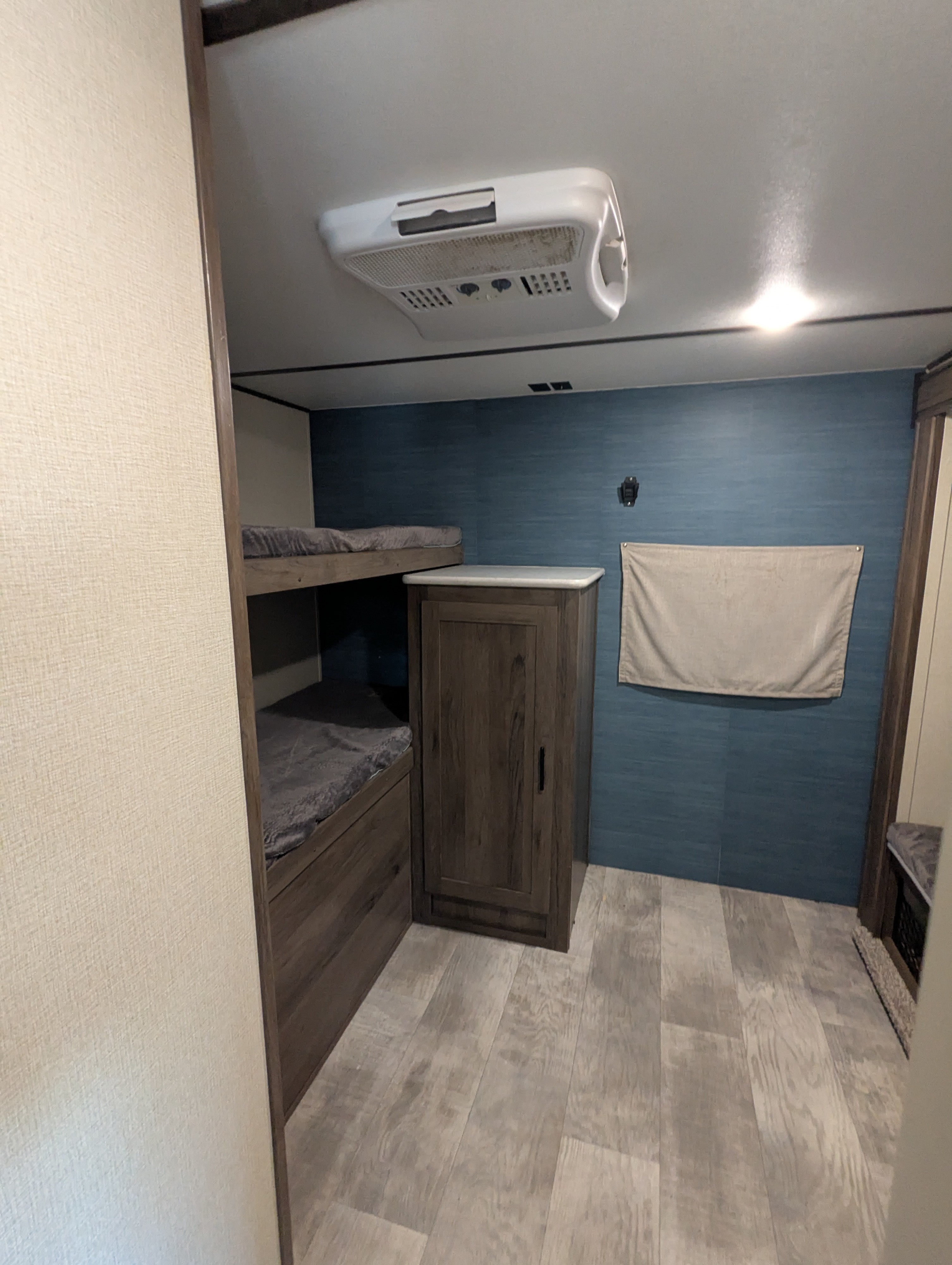 Cozy RV rental bunk area & storage. Features a blue accent wall, beds & ceiling AC unit, great for travel.. PrimeTime Tracer 2020