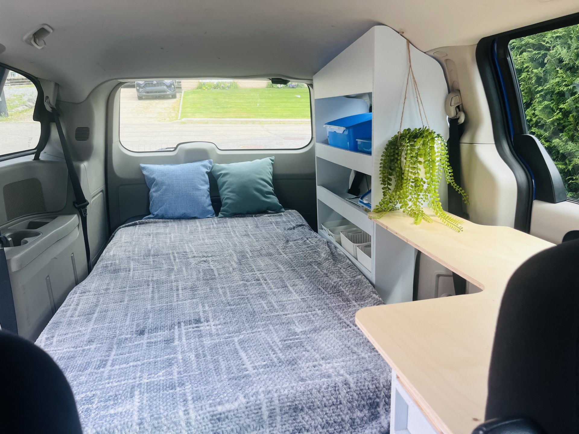 Compact minivan transformed for an rv rental: features a comfortable bed, storage shelves, and a work desk.. Dodge Grand Caravan SE 2013
