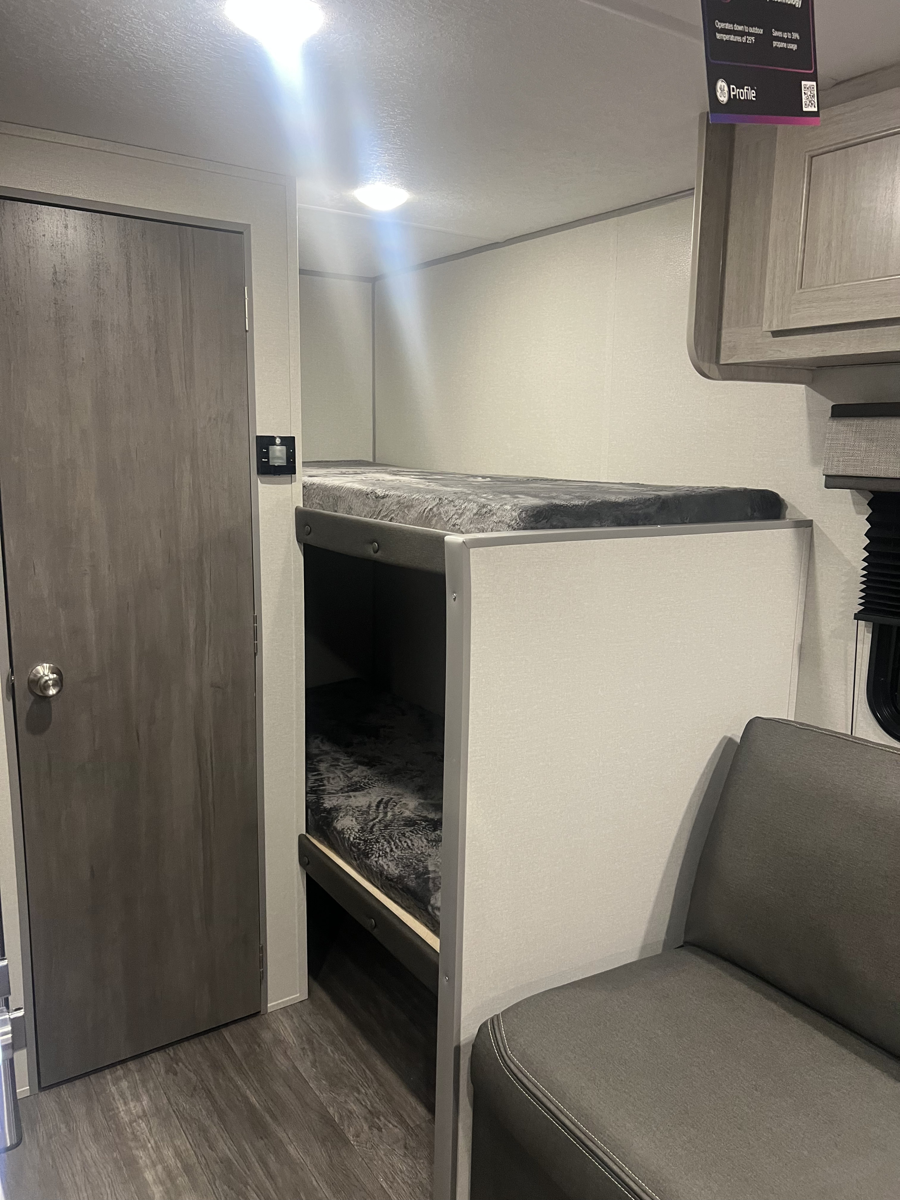 Inside an RV rental: a cozy space with two-tier bunk beds, a closed door, and a comfy sofa section. Perfect for family trips.. Forest River Aurora 2025