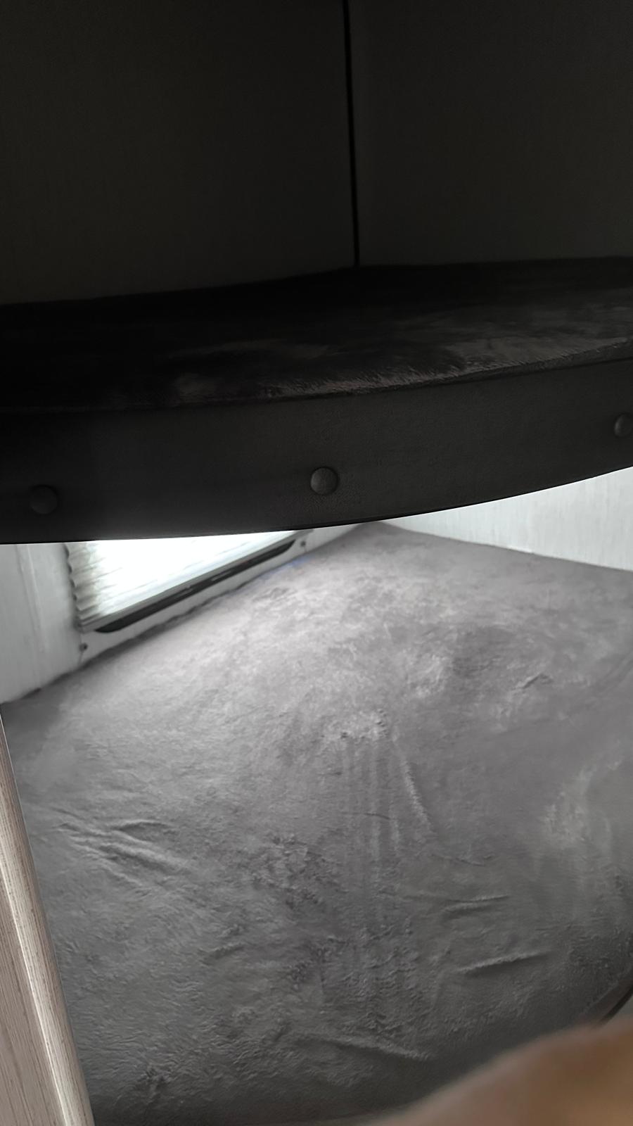 Underside of an RV rental bunk bed with grey mattress below and window blinds visible.. Heartland RVs Trail Runner 2021