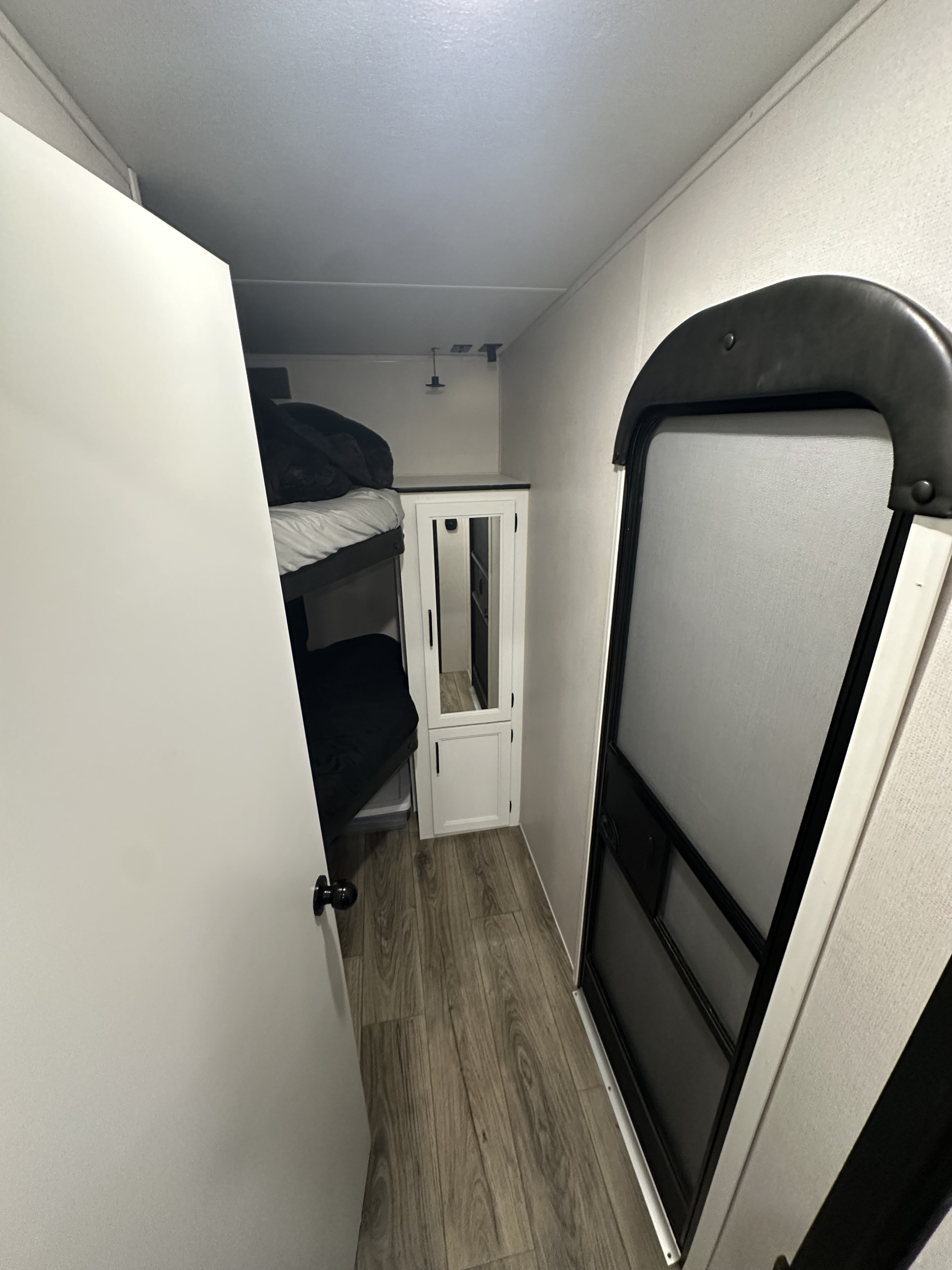 Interior of an rv rental with bunk beds, a mirrored cabinet, and an arched screen door on the right.. Crusader Lite 2021