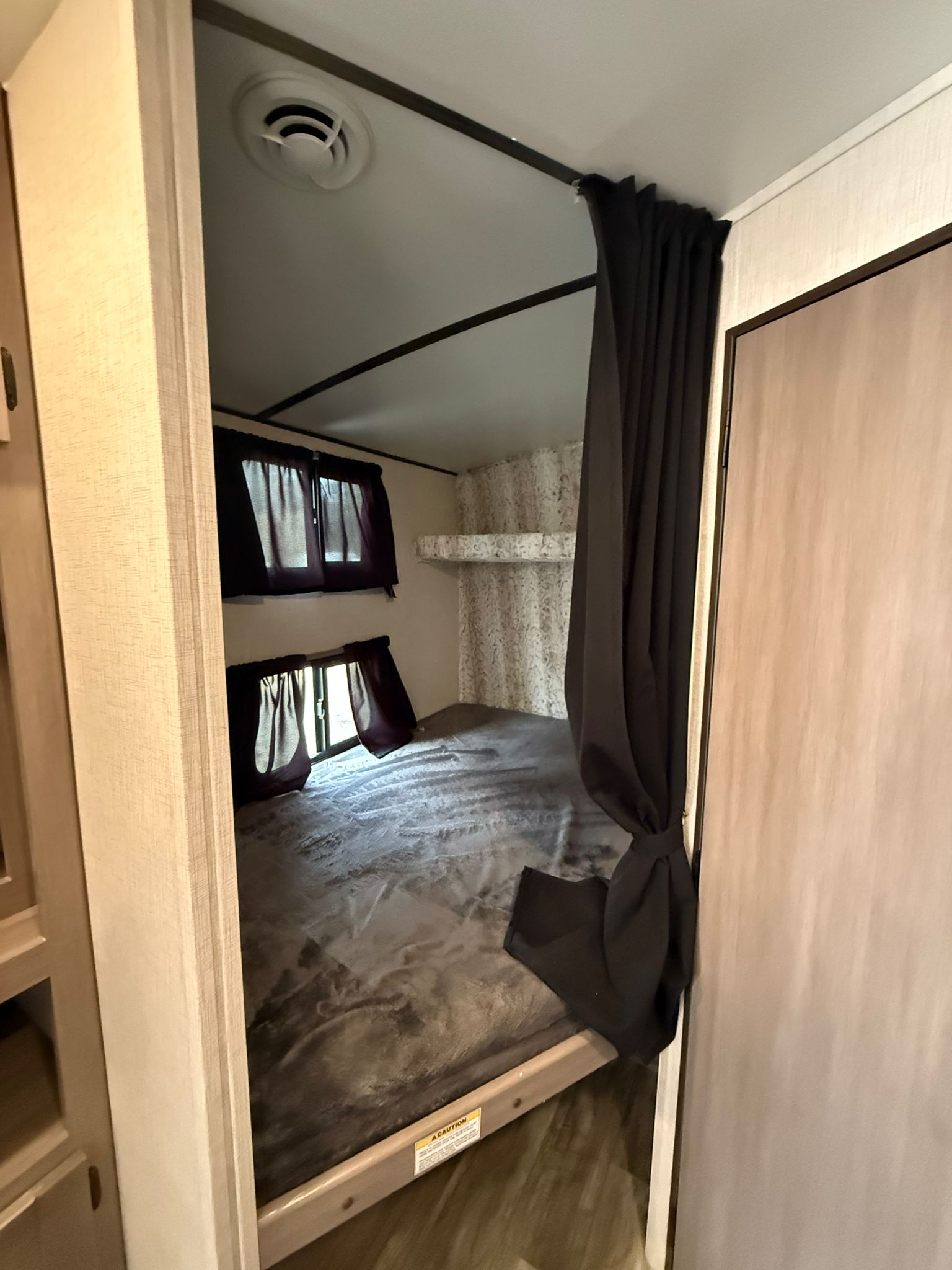 Cozy RV rental bunk beds with windows, a privacy curtain, and textured walls create a comfortable sleeping space.. sunset trail 242BH 2022