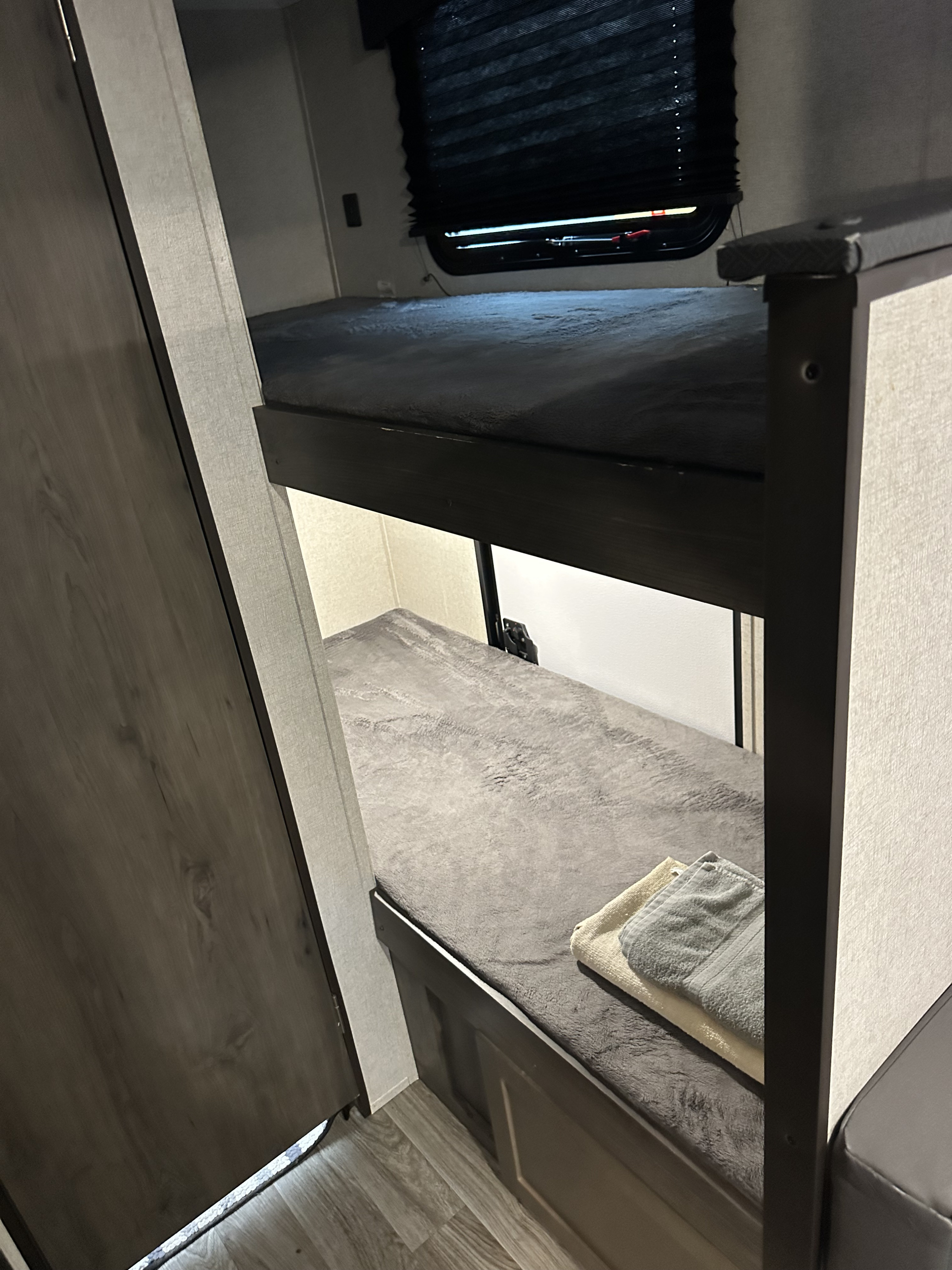 Inside an RV rental: cozy bunk beds with soft grey blankets and fresh towels, ideal for sleeping arrangements.. Cruiser RV Shadow Cruiser 2020