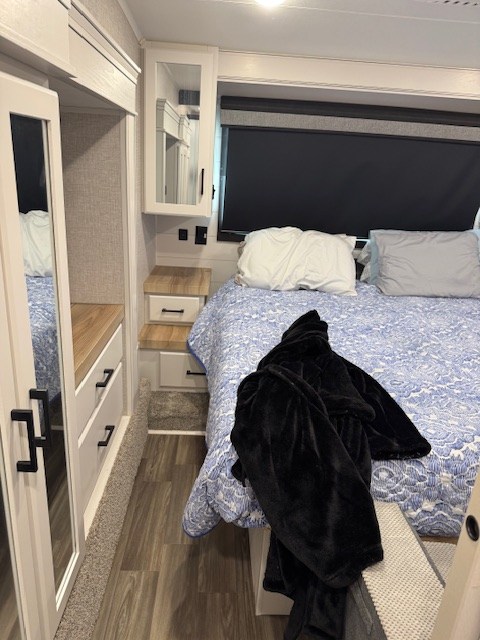 RV rental bedroom interior: Features a comfortable bed, built-in storage, and a window with a dark privacy shade.. Jayco Eagle 2024
