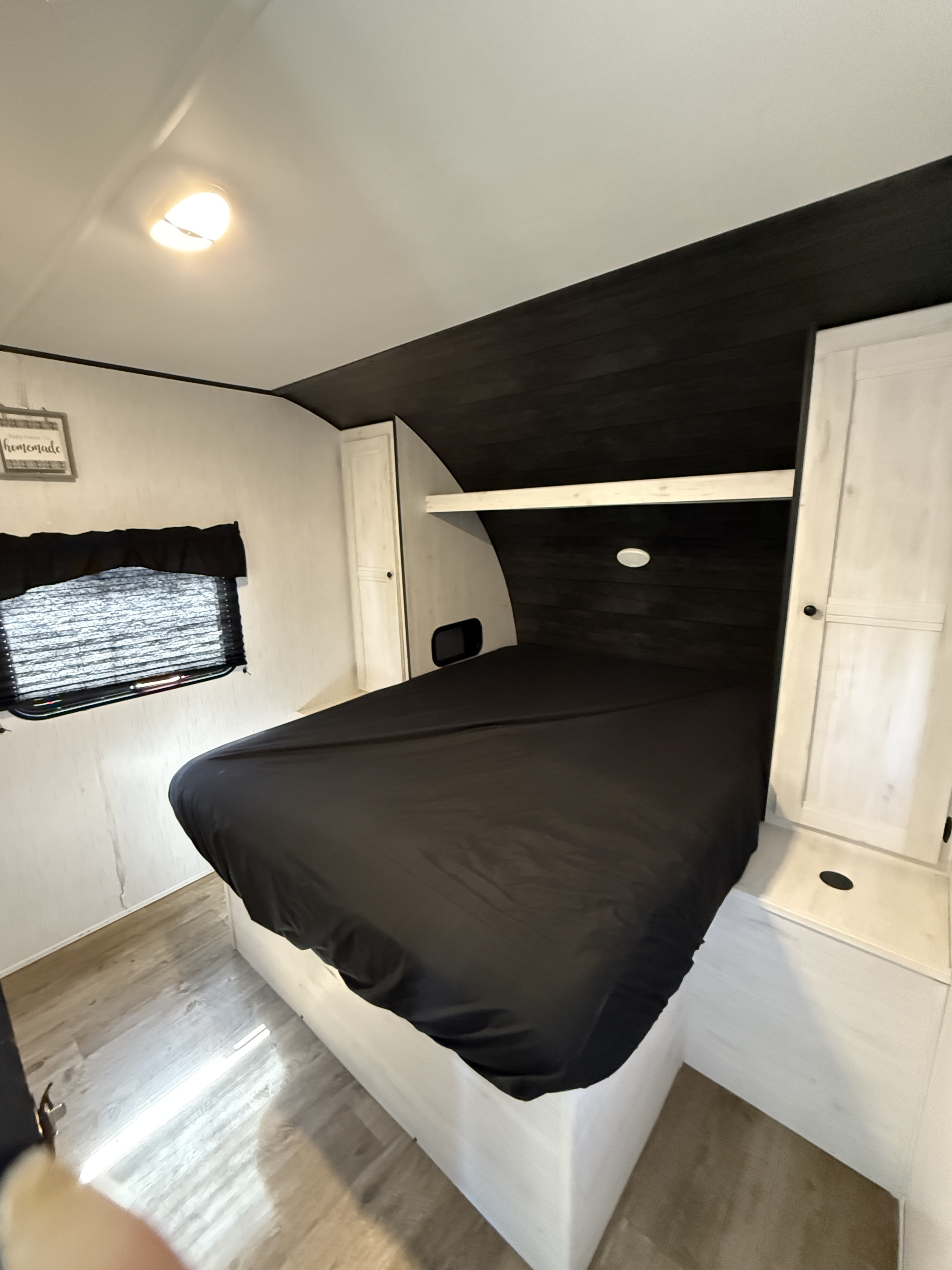 Cozy RV rental bedroom with a comfortable bed, white cabinetry, and dark wood paneling for your next adventure.. Heartland Trail Runner 2022