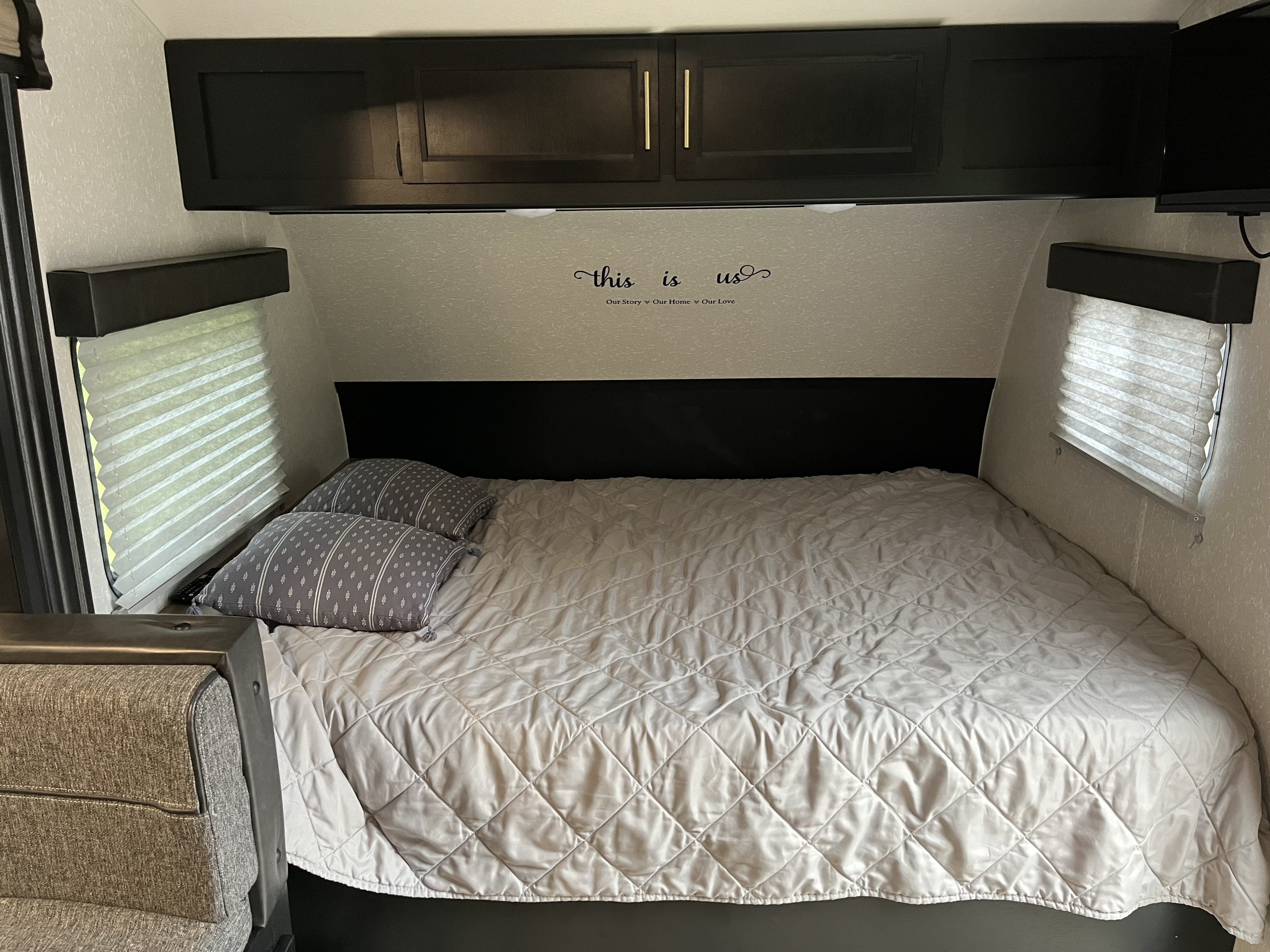 RV rental: a neatly made bed with grey pillows, dark cabinets, & window blinds in a modern bedroom setup.. Forest River Cherokee Wolf Pup 2021