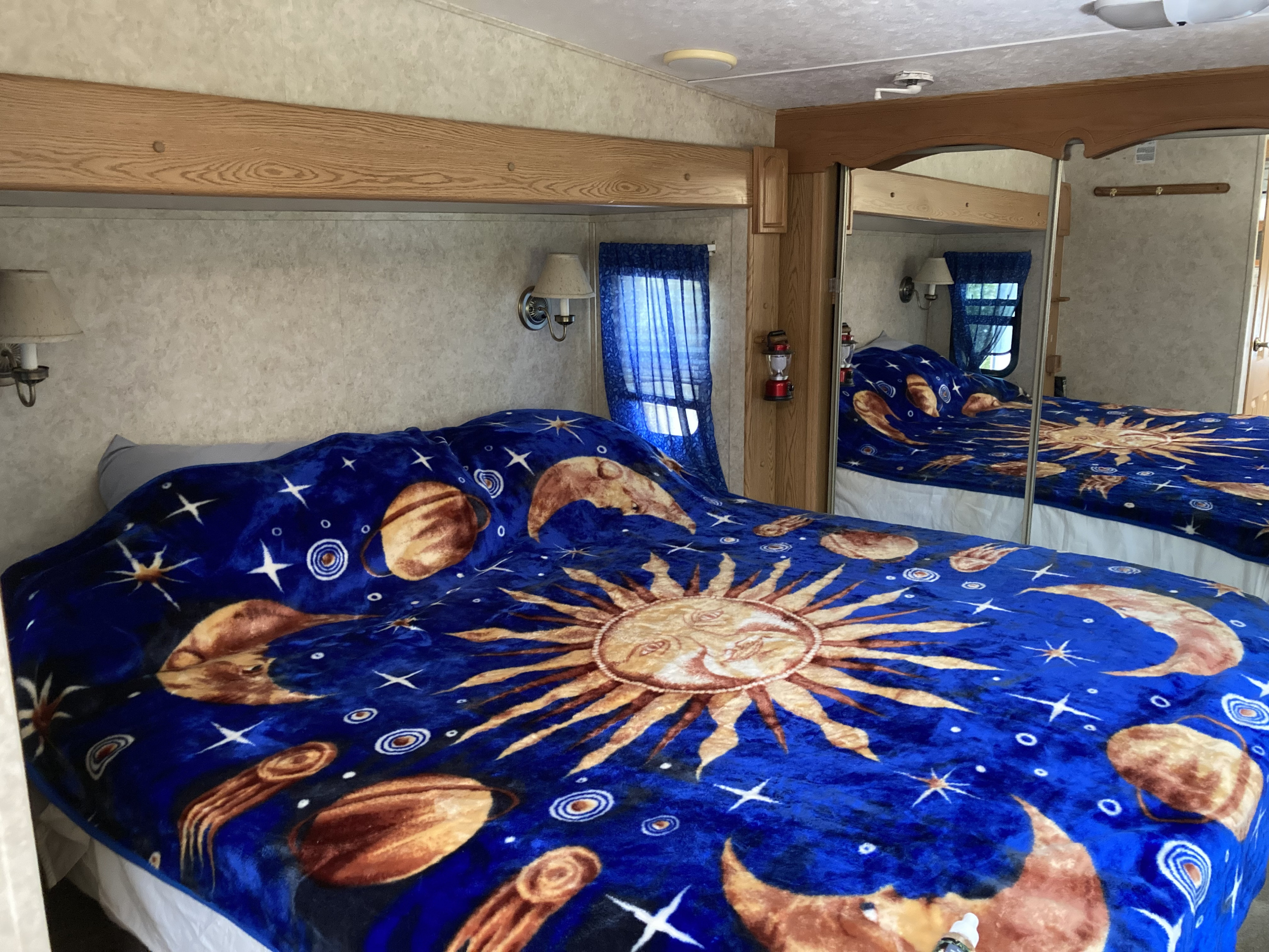 Inside this RV rental, a bed with a vivid celestial blanket and mirrored closet offers a unique sleep space.. Keystone 2955RL 2006