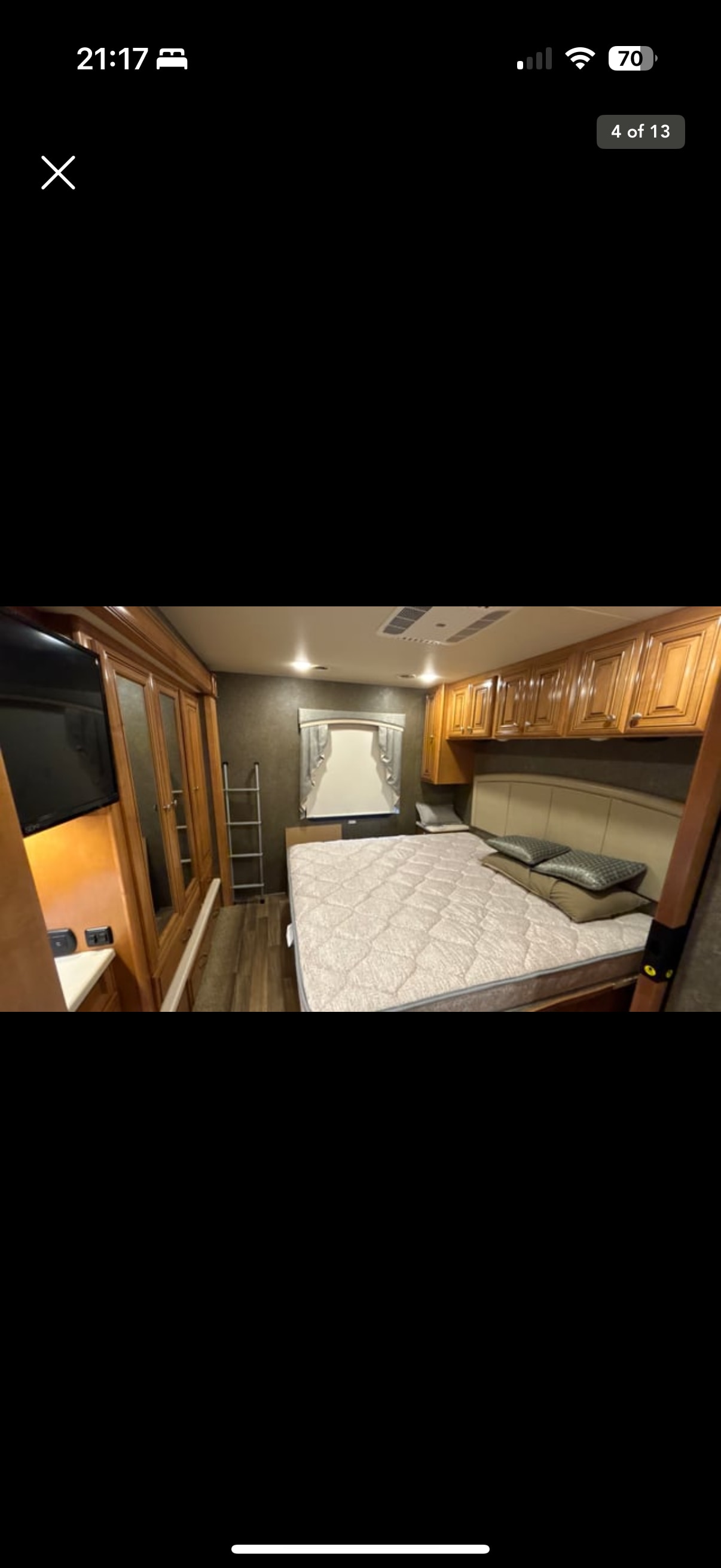 RV rental bedroom with a comfortable bed, overhead cabinets, TV, and closet. Compact yet functional.. Thor Miramar 2017
