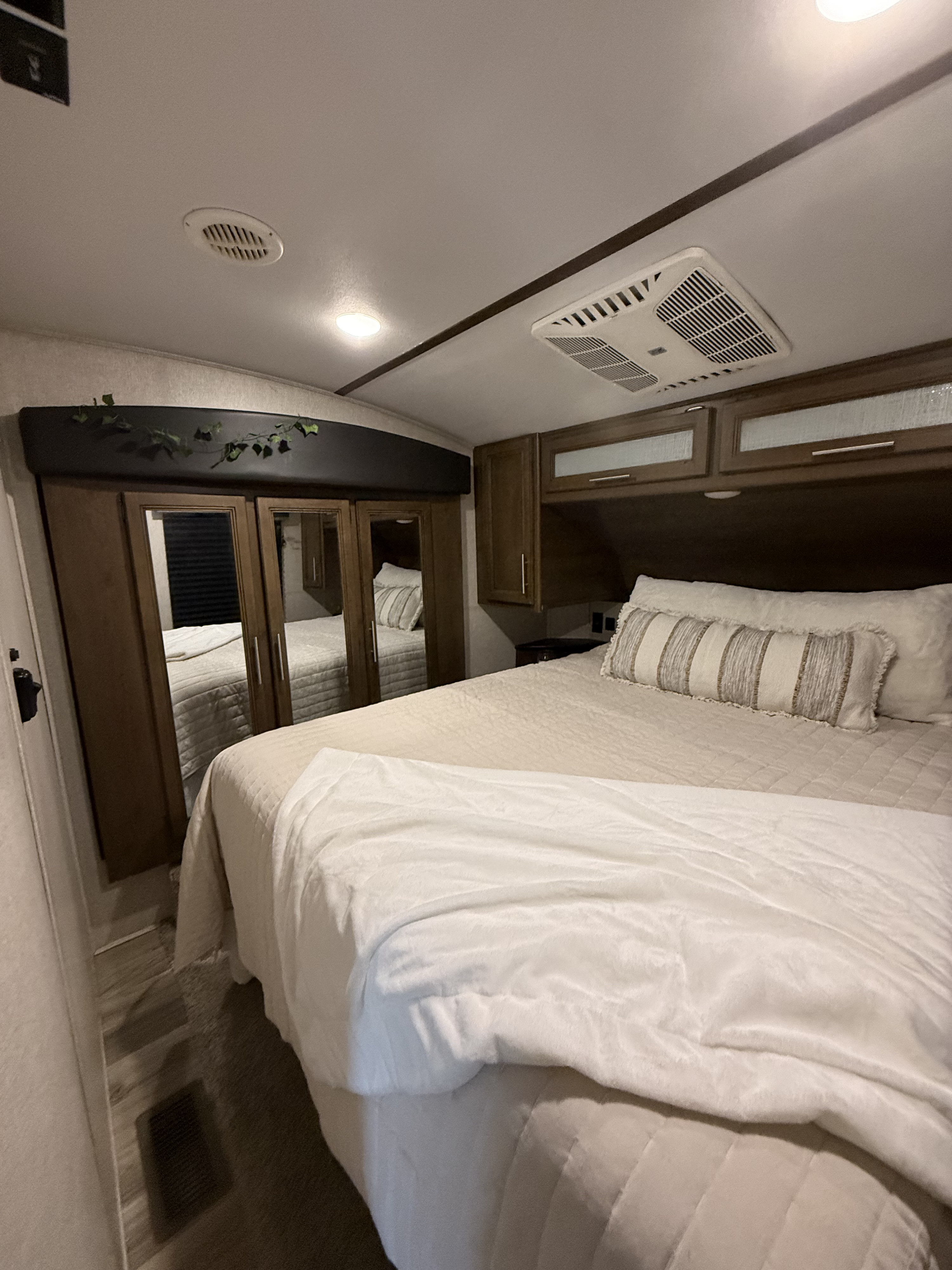 Comfortable RV rental bedroom with AC, mirrored wardrobe, and overhead storage, perfect for your next adventure.. Keystone RV Cougar 2021