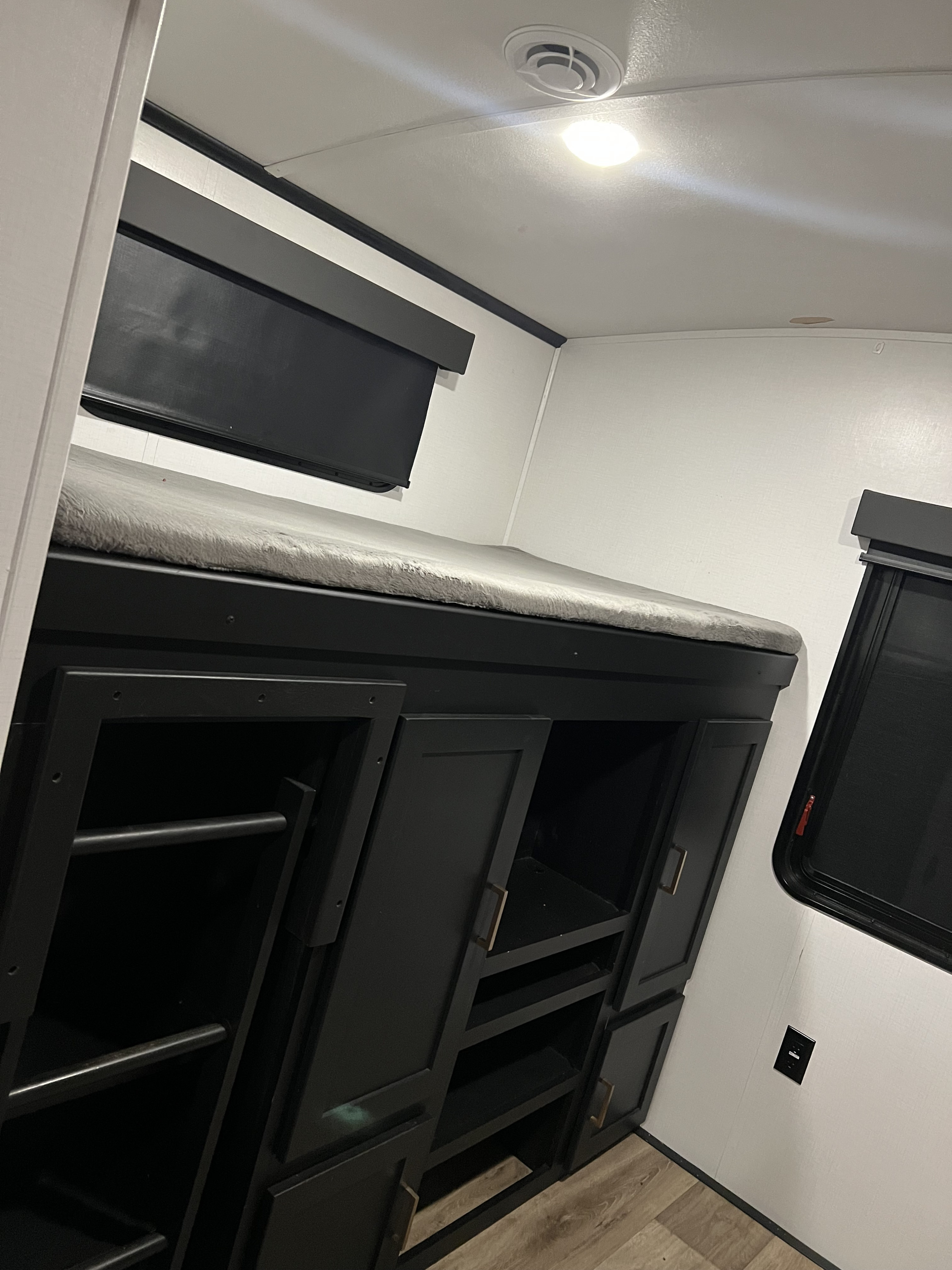 RV rental bunk area with plush mattress, built-in storage, and window. Ideal compact living space.. Keystone RV Outback 2022